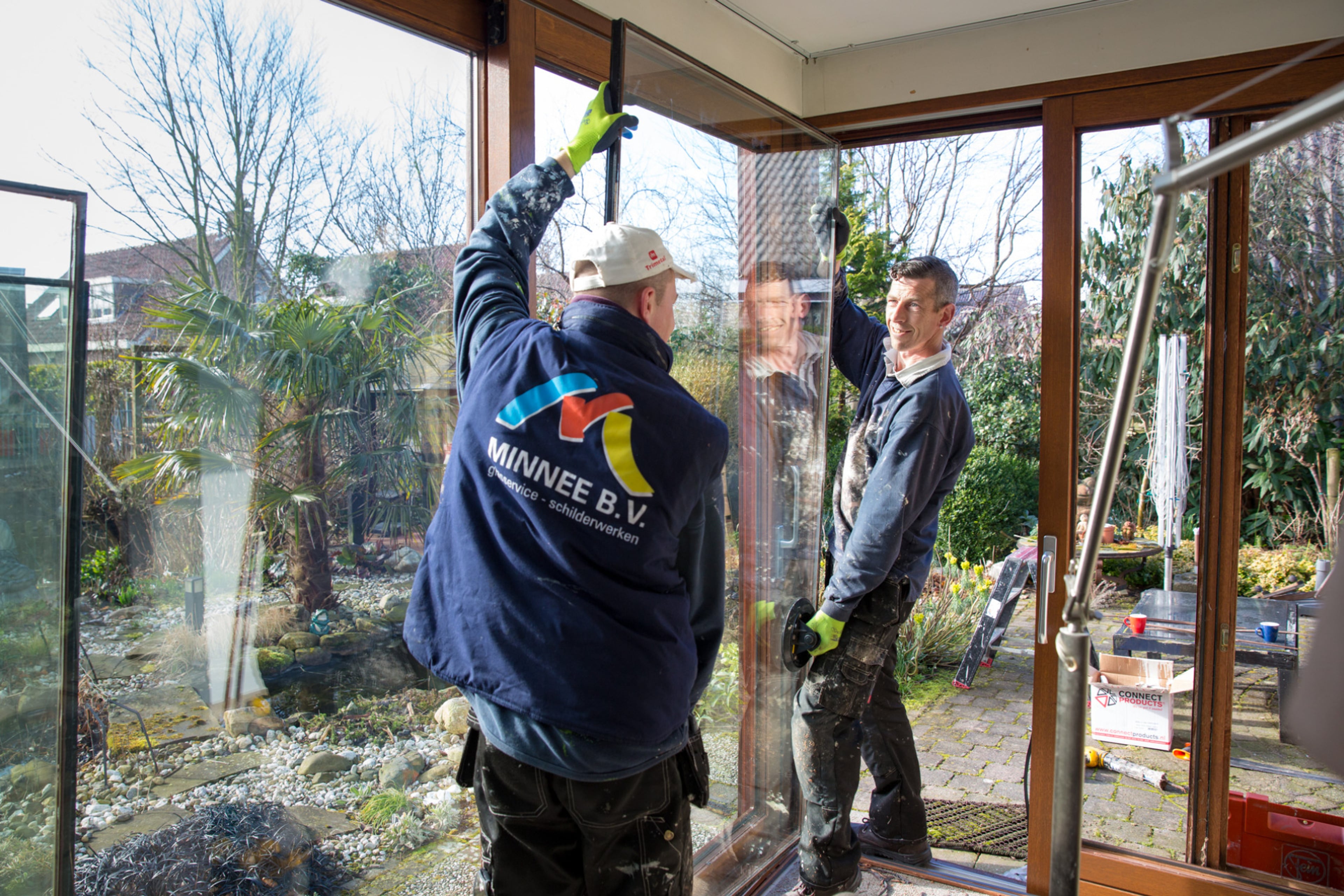 Mannen plaatsen goed isolerend HR++ glas in een houten kozijn.