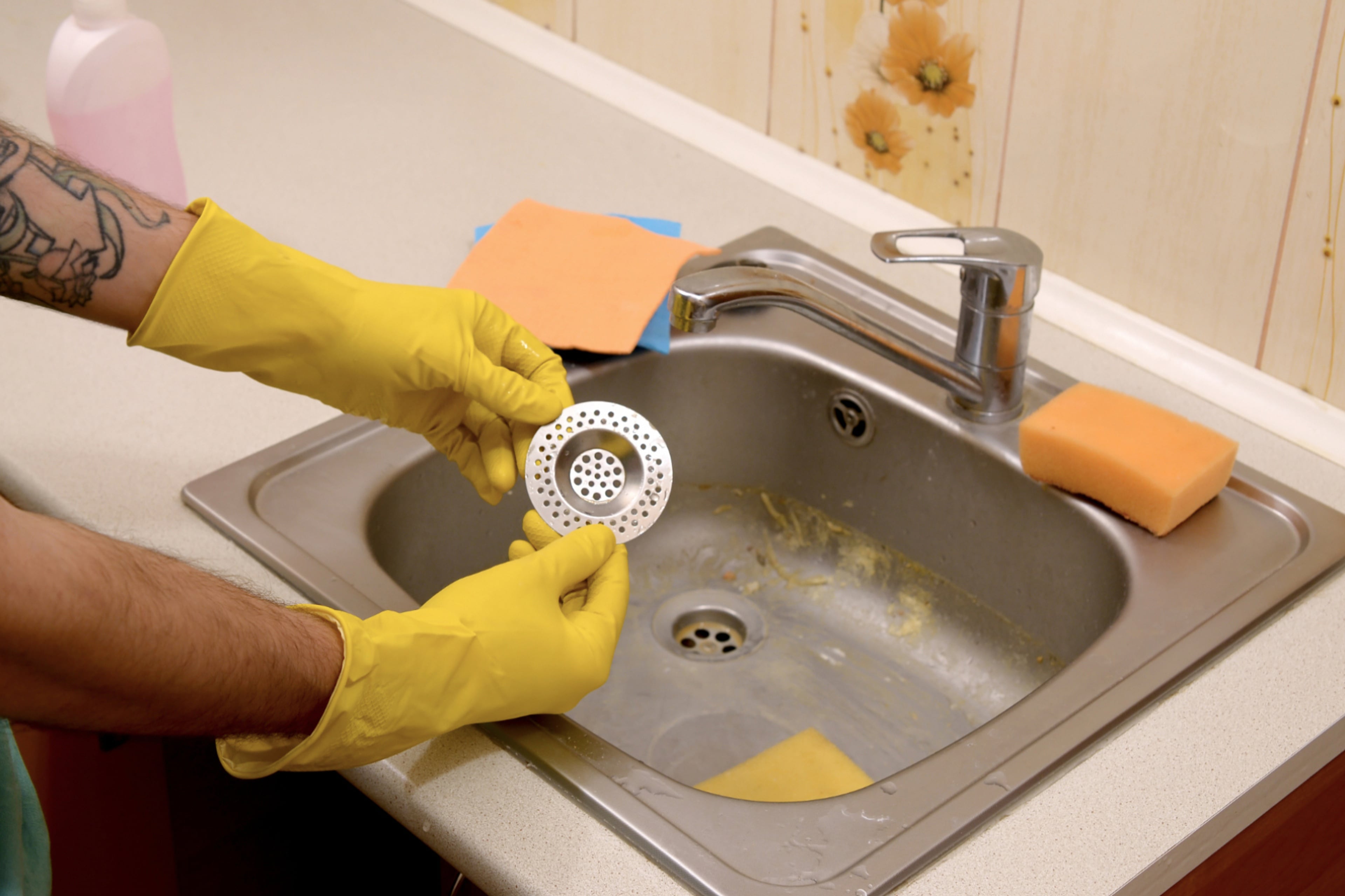 Gootsteen met iemand die een zeefje demonstreert. Voorkom dat er plastic en ander afval in het riool terecht komt, door een zeefje in je afvoer te leggen.