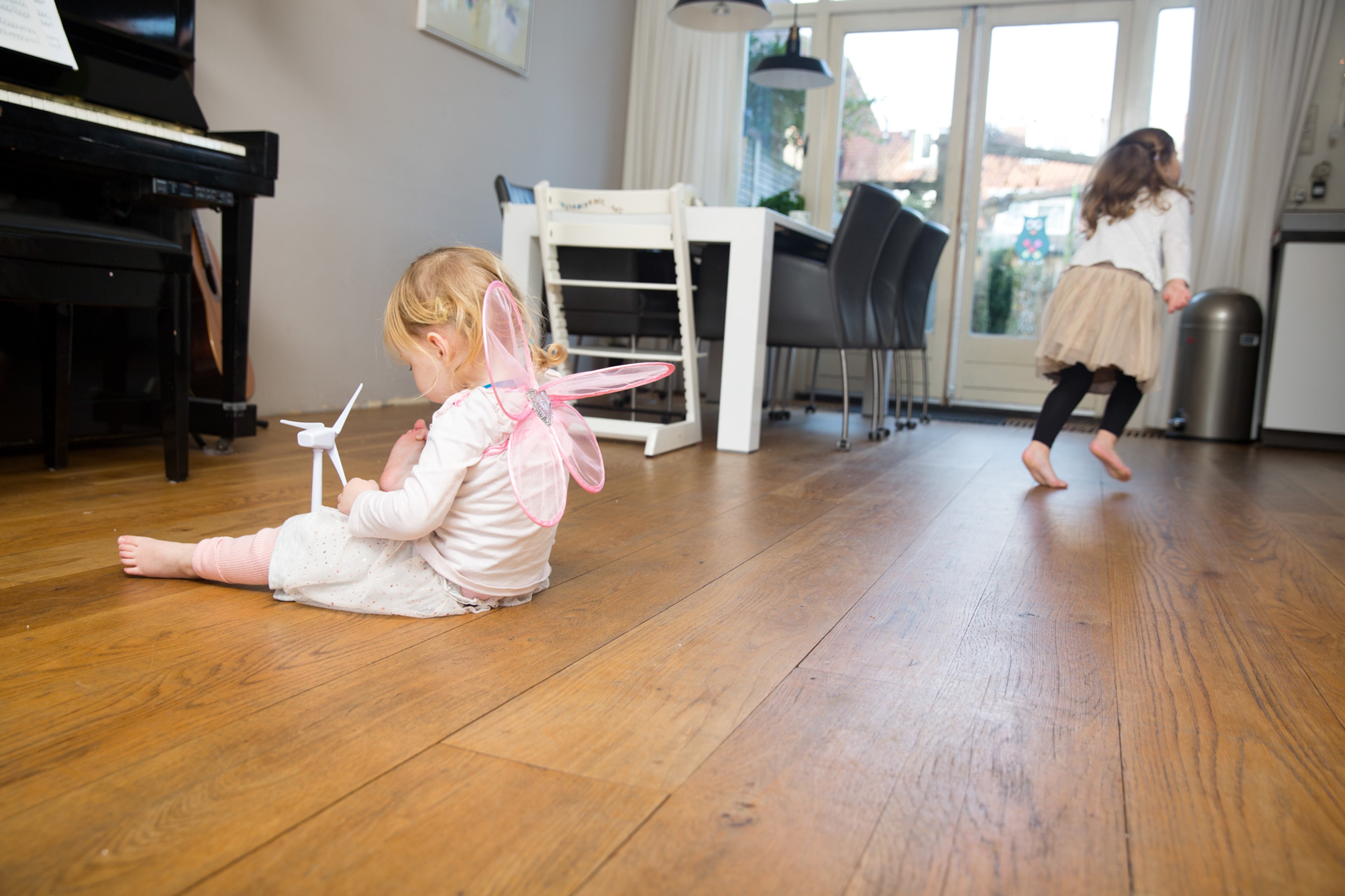 Kinderen zitten op de vloer en spelen met windmolen.