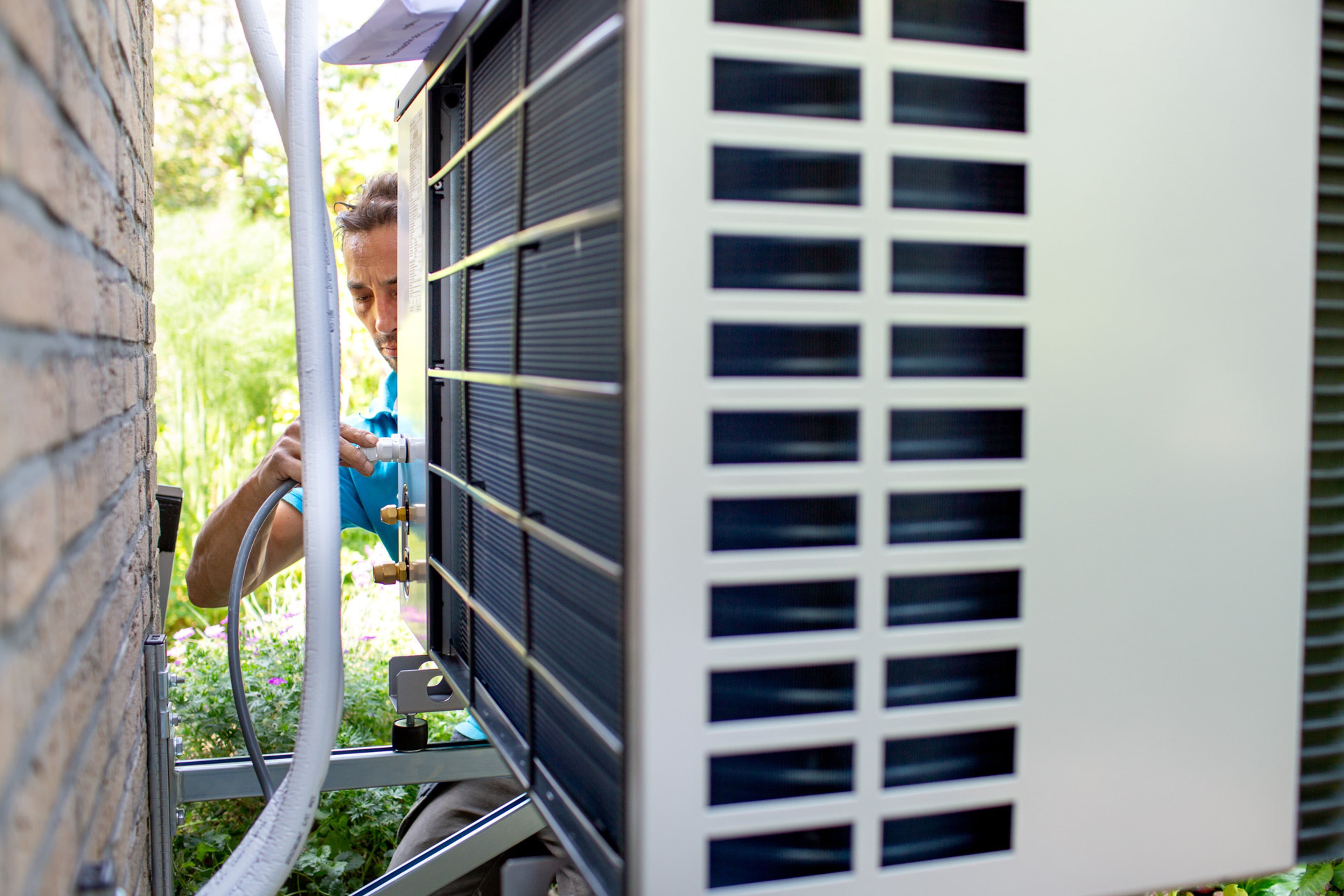 Installateur sluit buitenunit warmtepomp aan