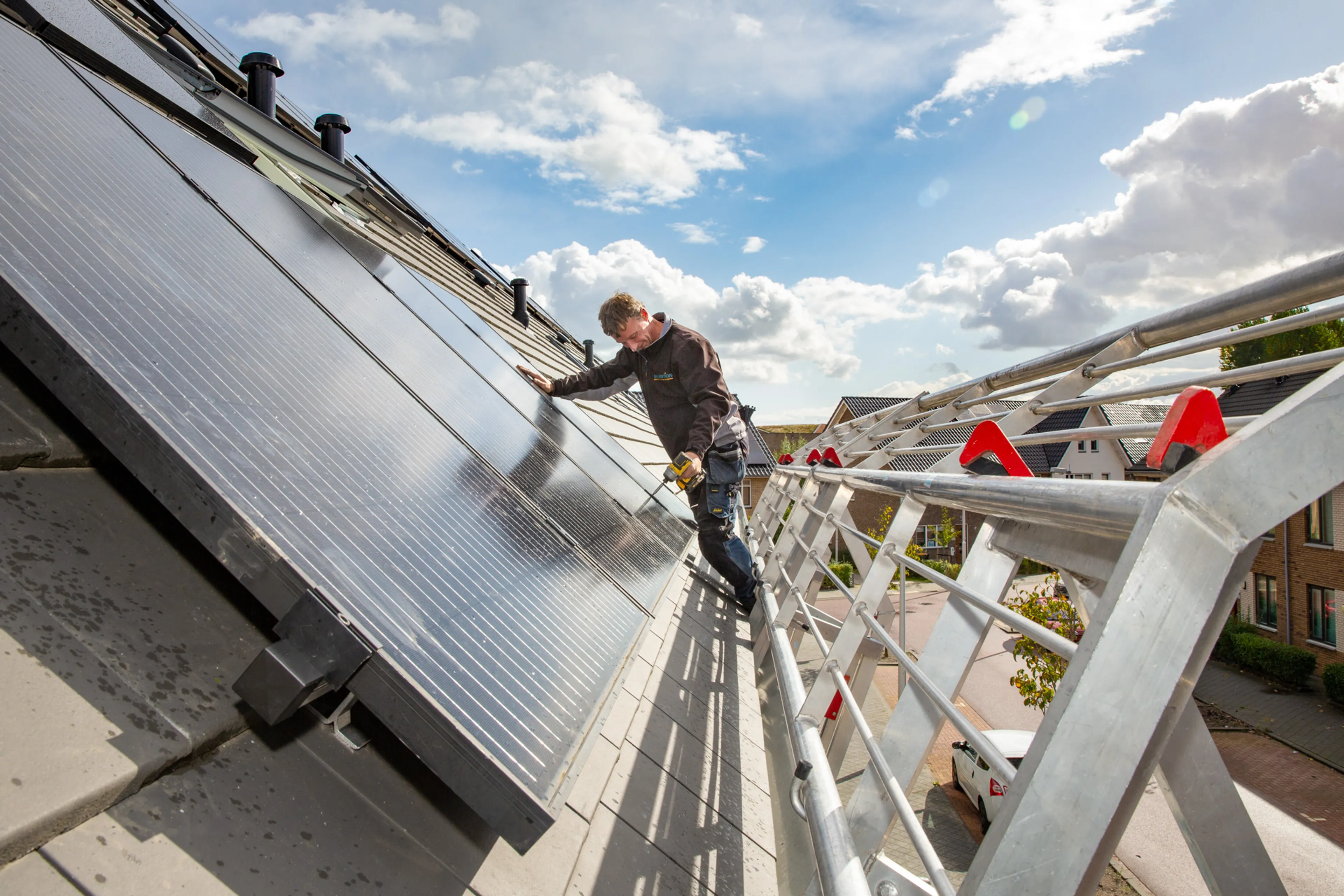 Man installeert zonnepanelen op dak. Vind een betrouwbare installateur.