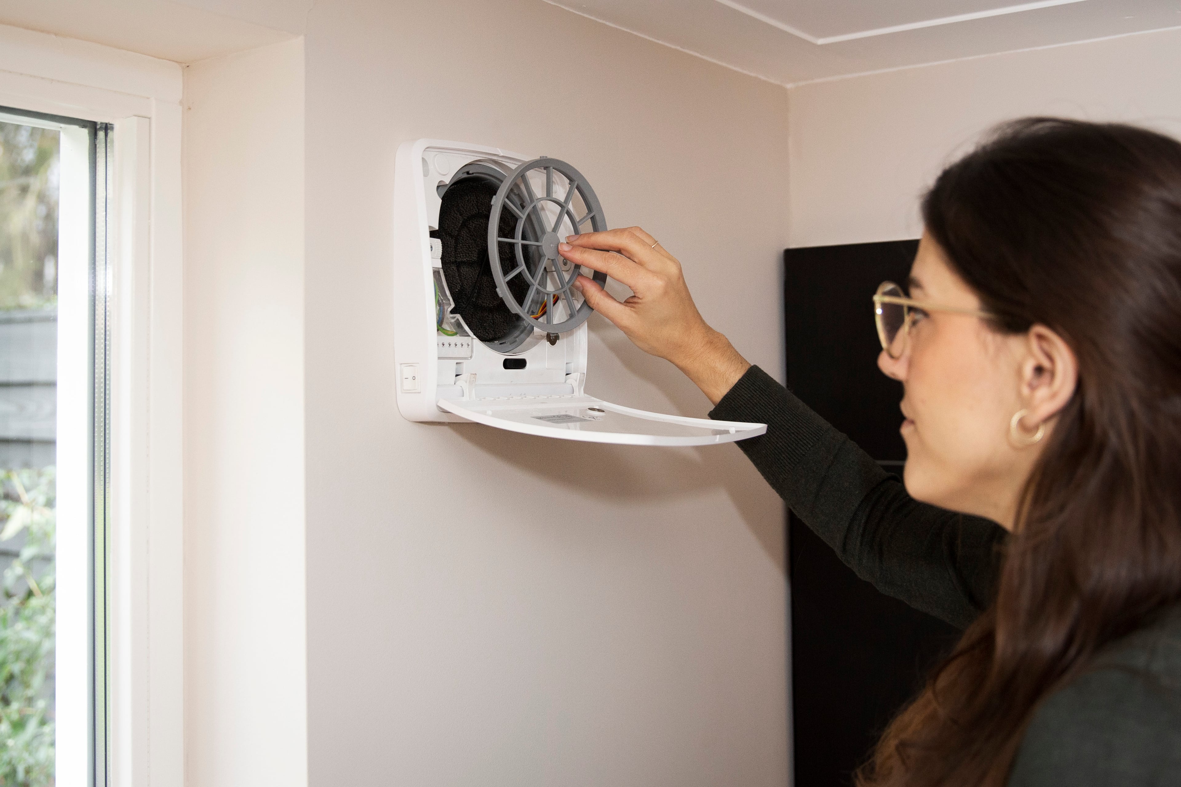 Vrouw bij ventilatiesysteem aan de muur