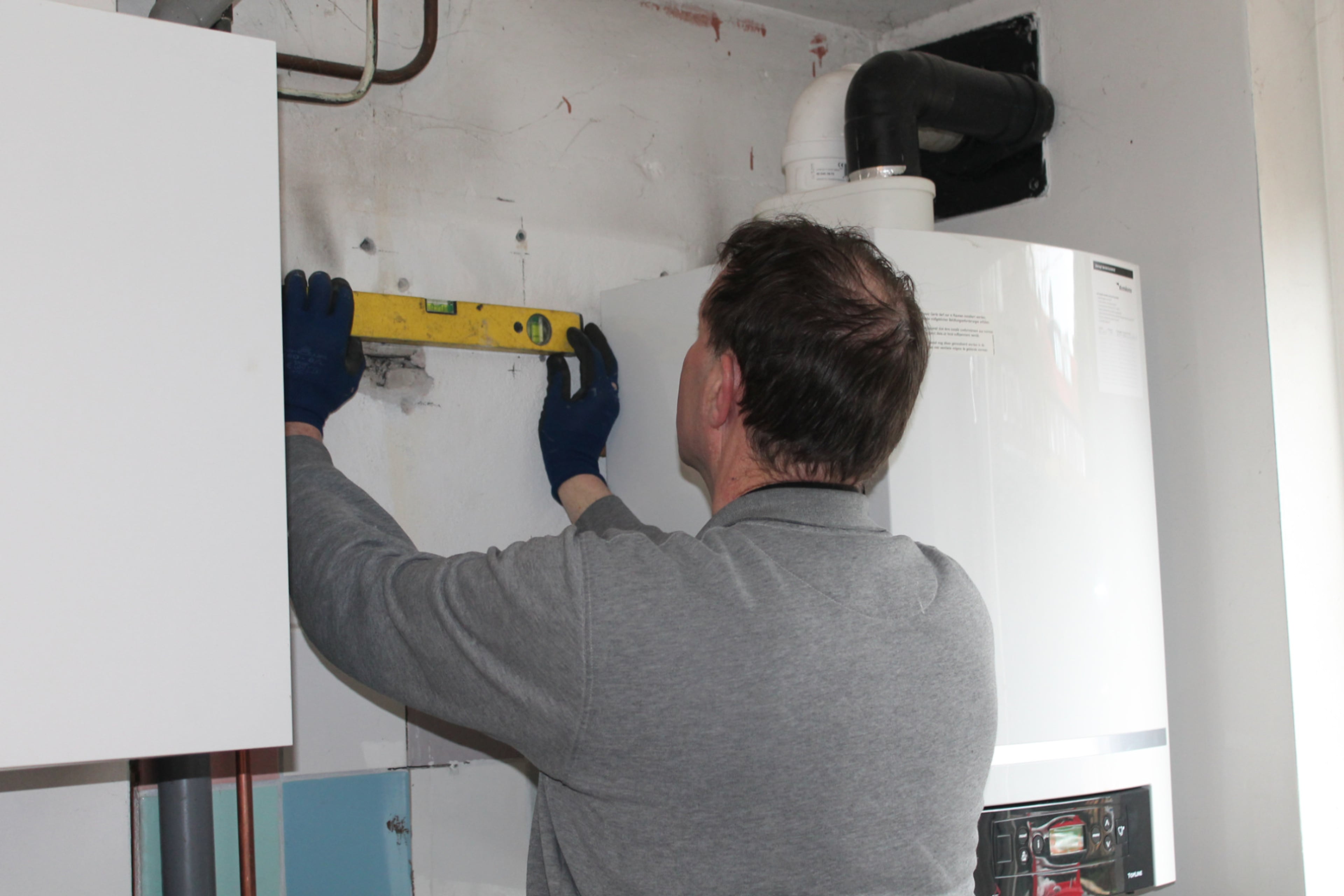 Monteur zorgt dat de warmtepomp waterpas hangt
