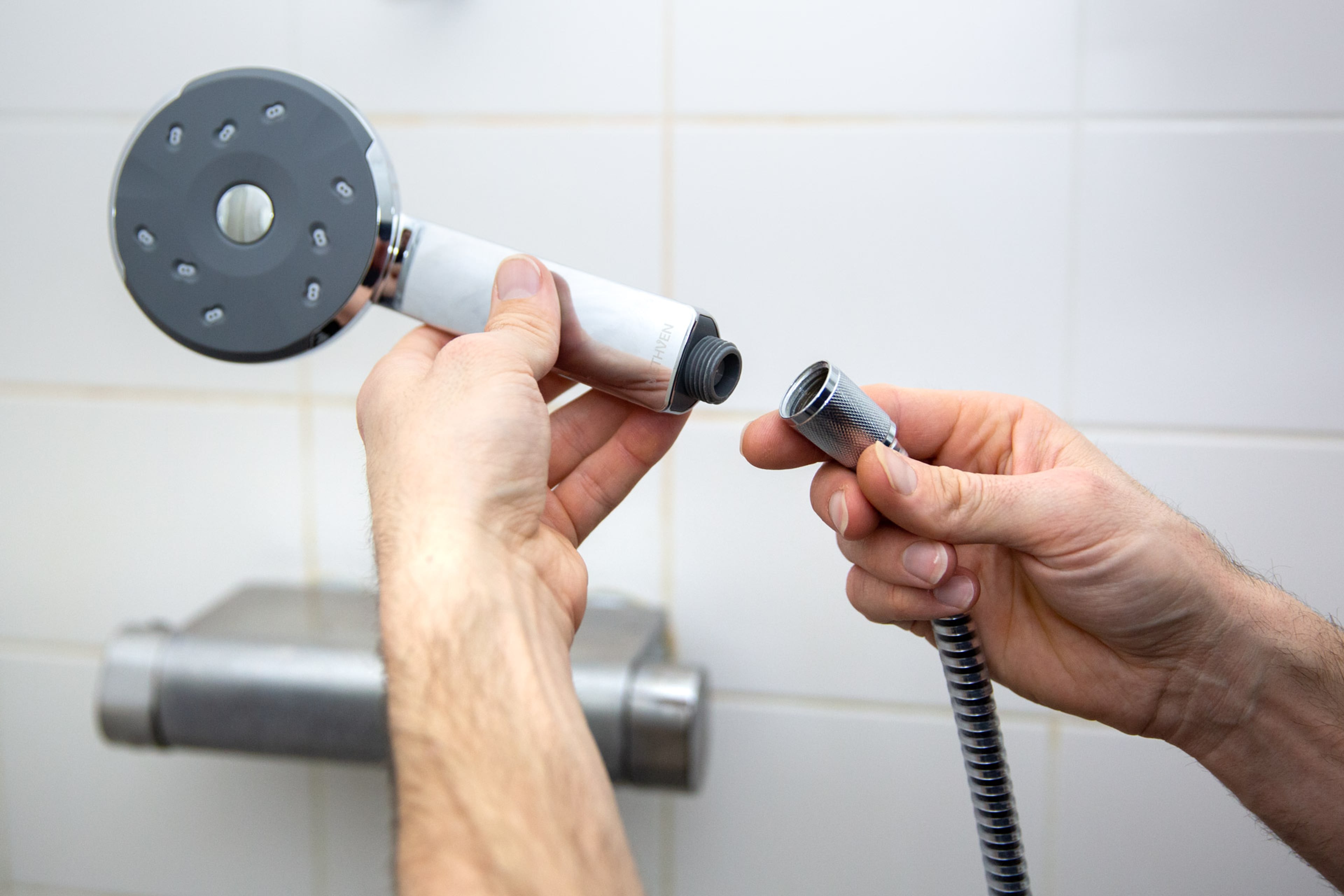 Handen die waterbesparende douchekop monteren. Makkelijk water besparen onder de douche.