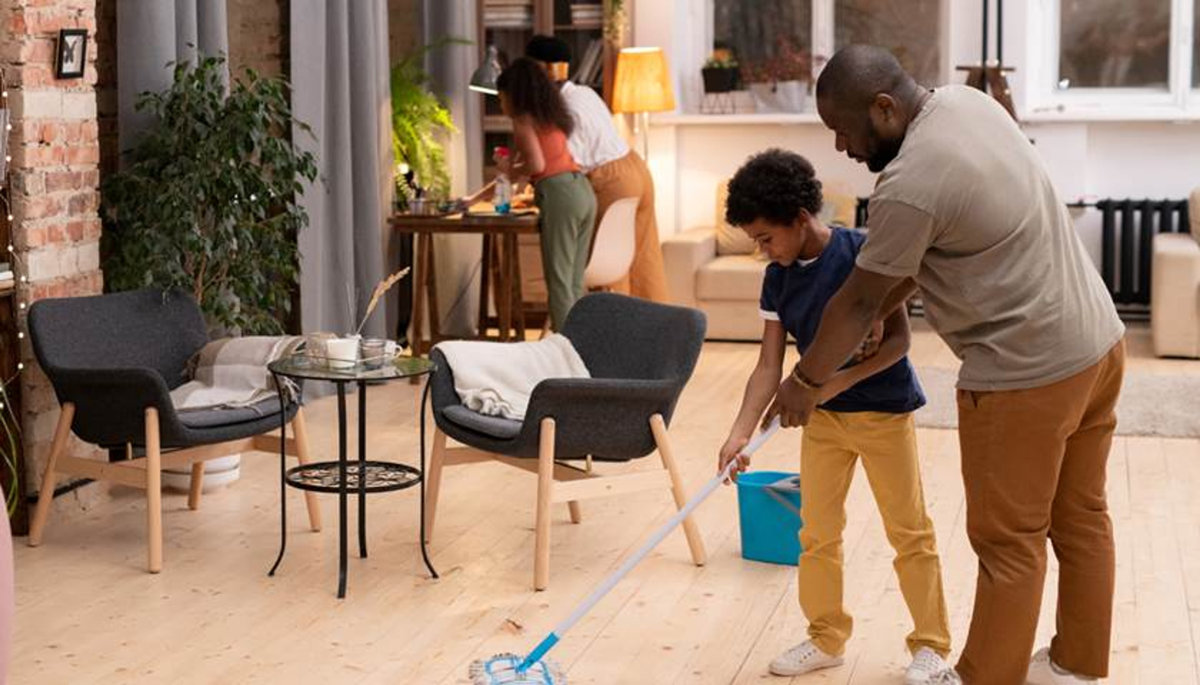 Vader en zoontje dweilen samen de vloer. Schoonmaken is goed voor de hygiëne in huis.