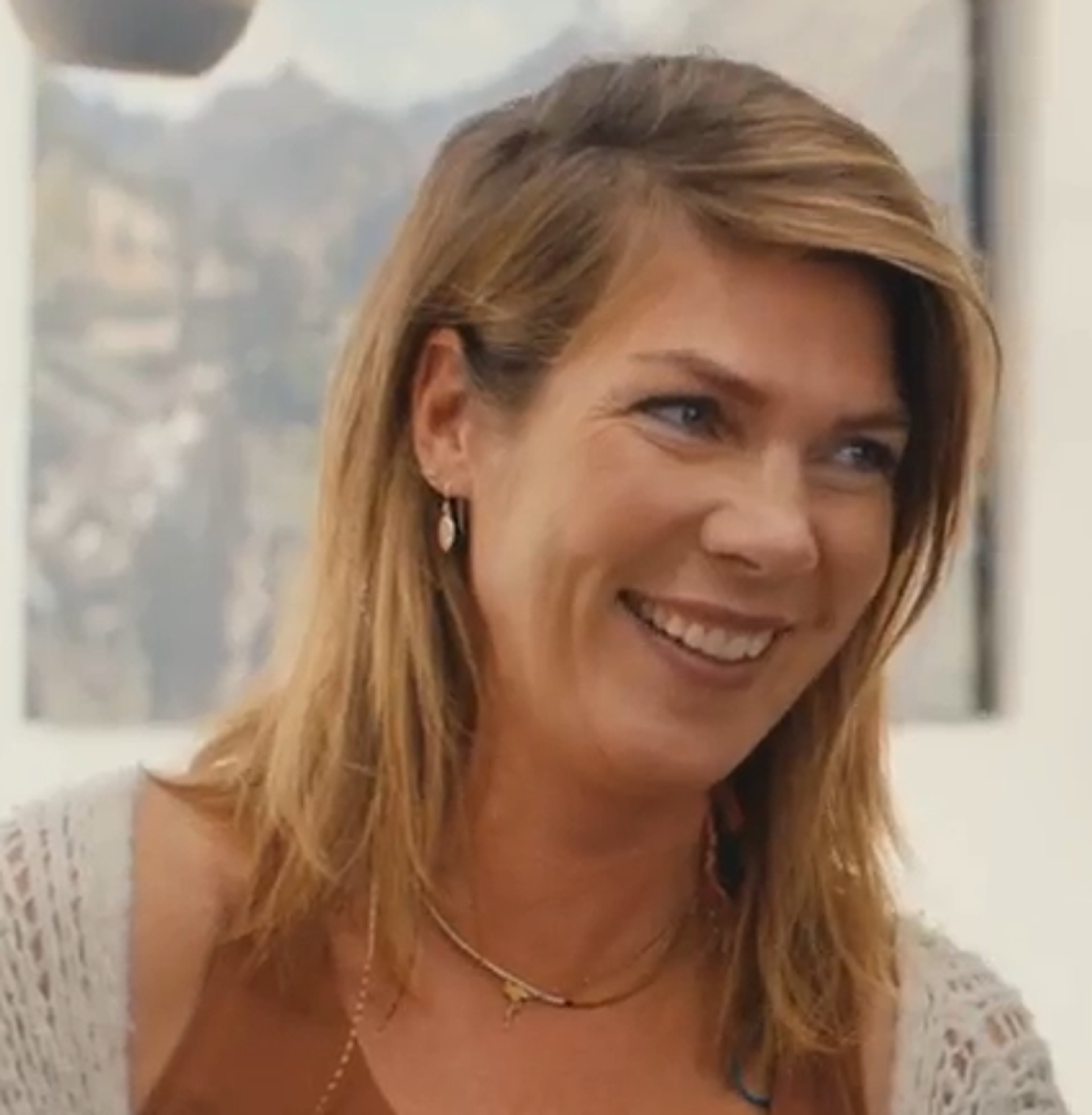 Portret van een lachen vrouw met bruin haar, een wit vest en bruin hemd. Ze is de moeder van een gezin voor een houtstookcampagne.