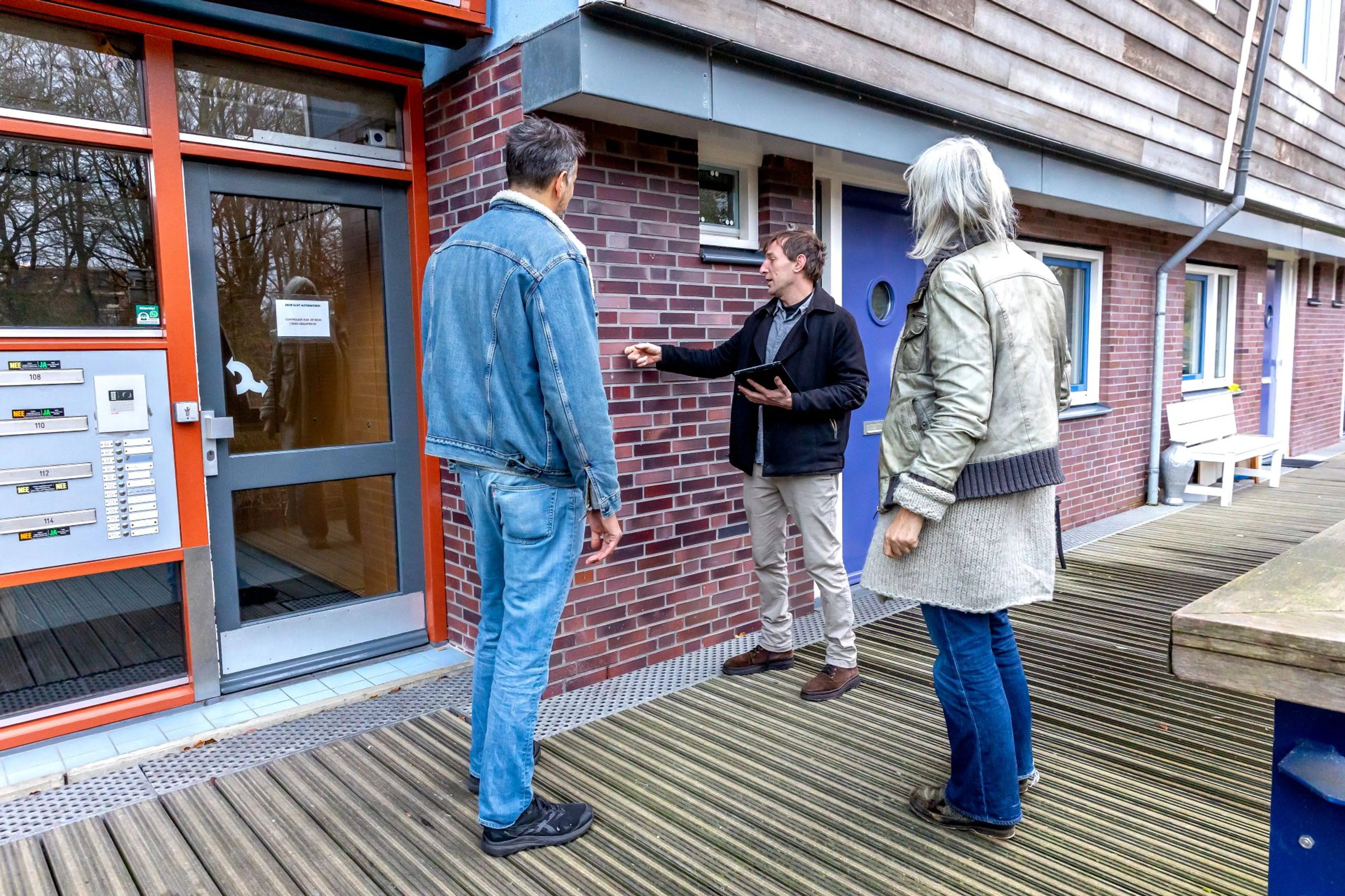 Drie mensen praten bij een voordeur