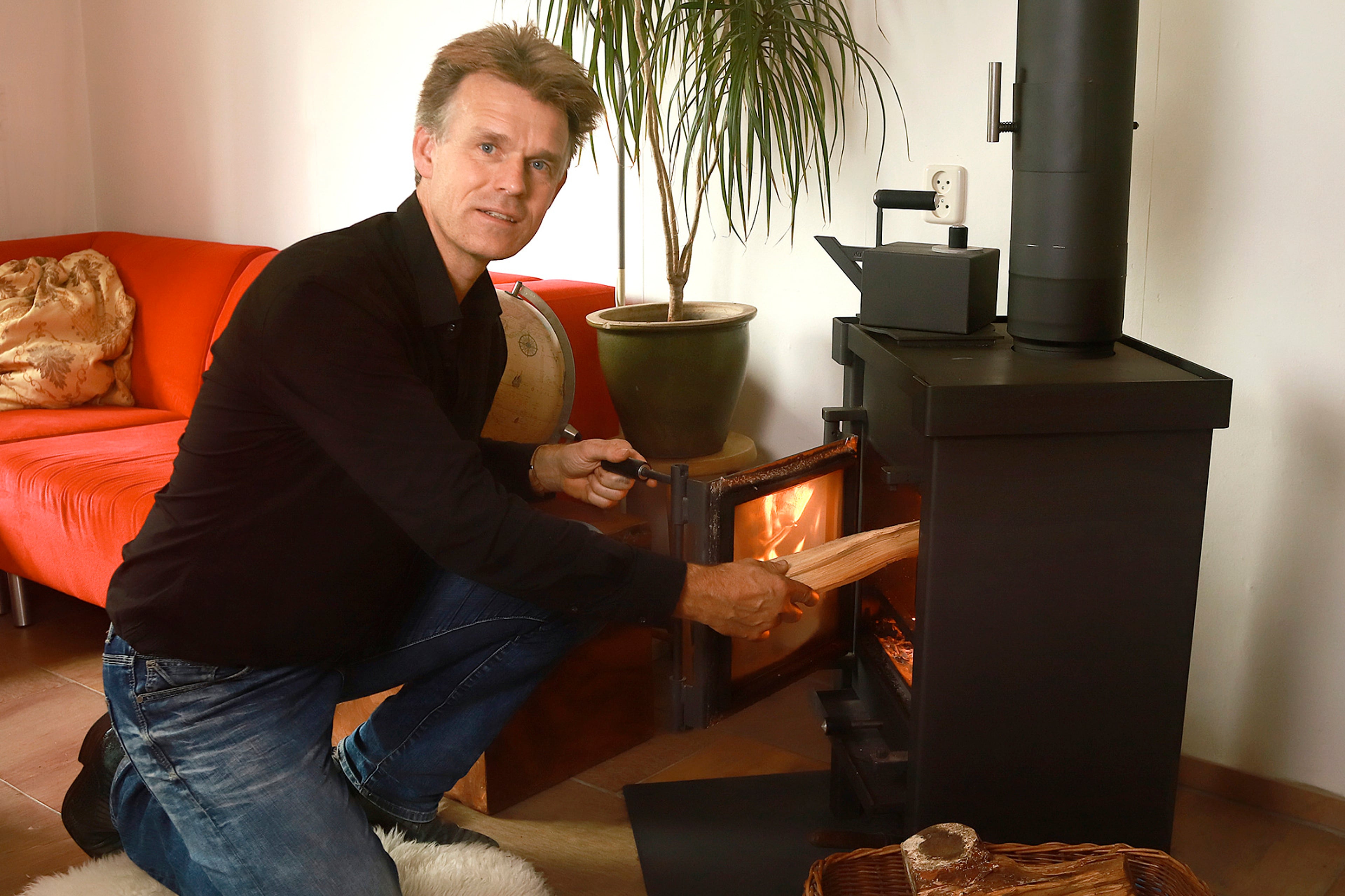 Man steekt houtkachel aan. Met de 10 stooktips zorg je voor minder overlast van hout stoken.
