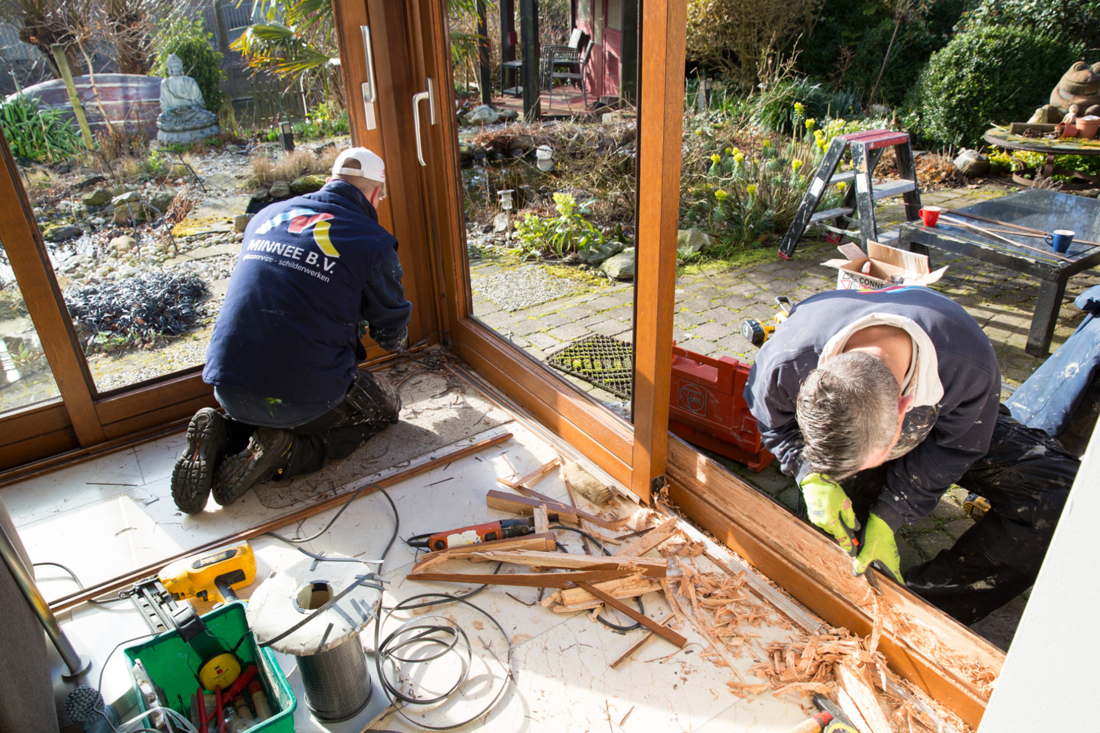 Mannen fresen gleuven in het kozijn om isolerend HR++ glas te plaatsen.