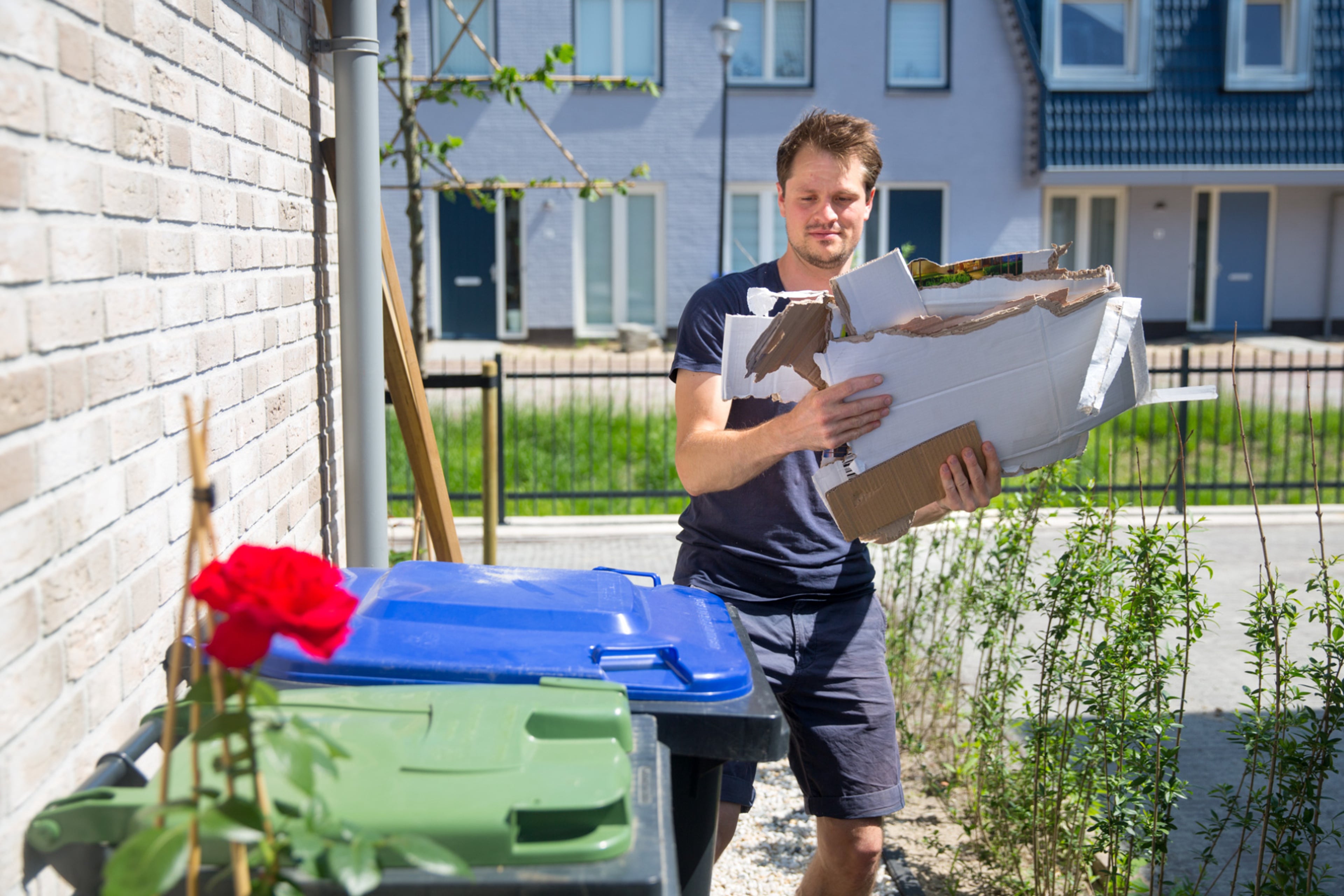 Man komt aanlopen naar een afvalbak met groene deksel en één met blauw deksel, om zijn karton weg te gooien. Bepaald materiaal mag wel bij het papier en karton, ander materiaal moet bij restafval of plastic.