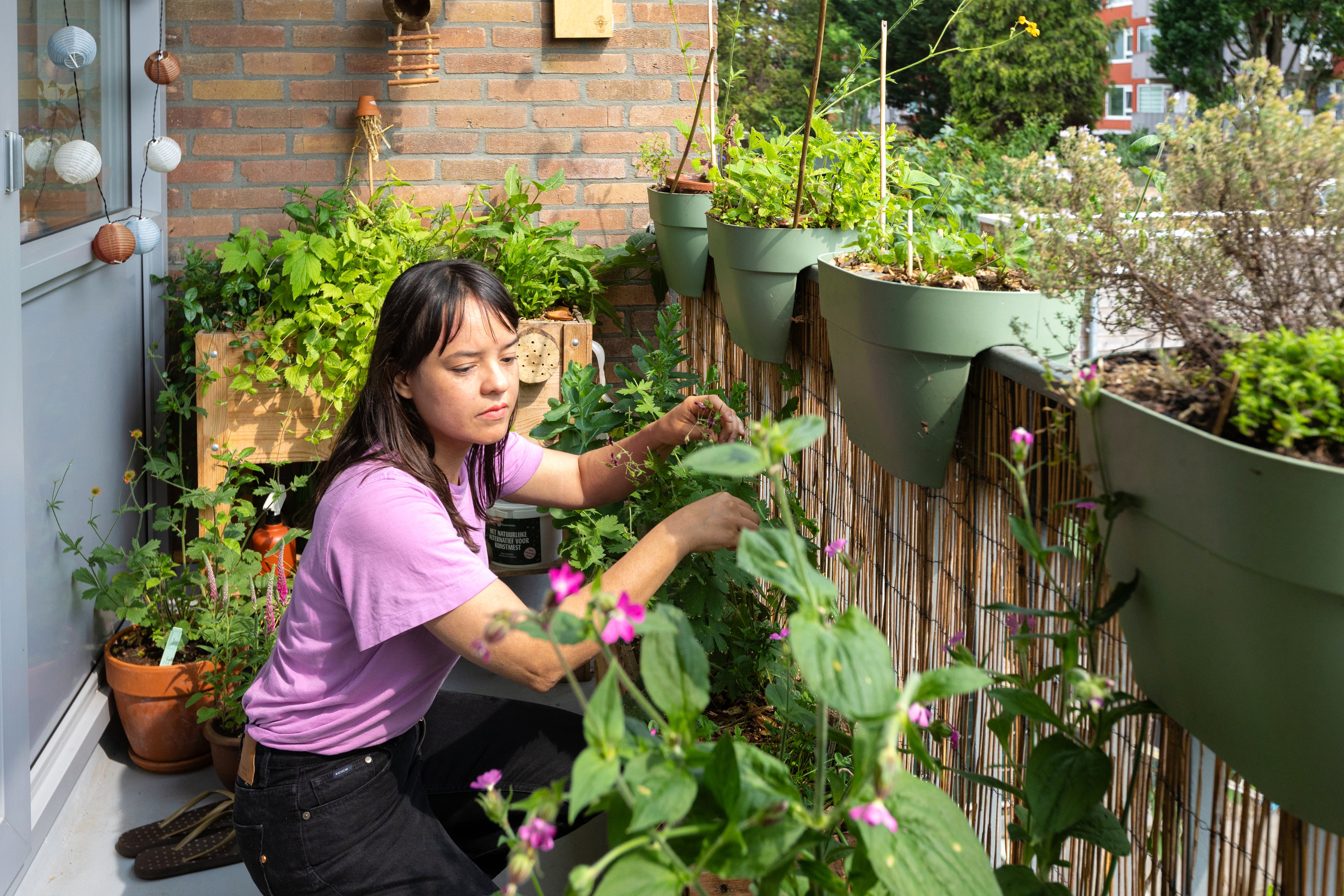 vrouw op groen balkon bij planten
