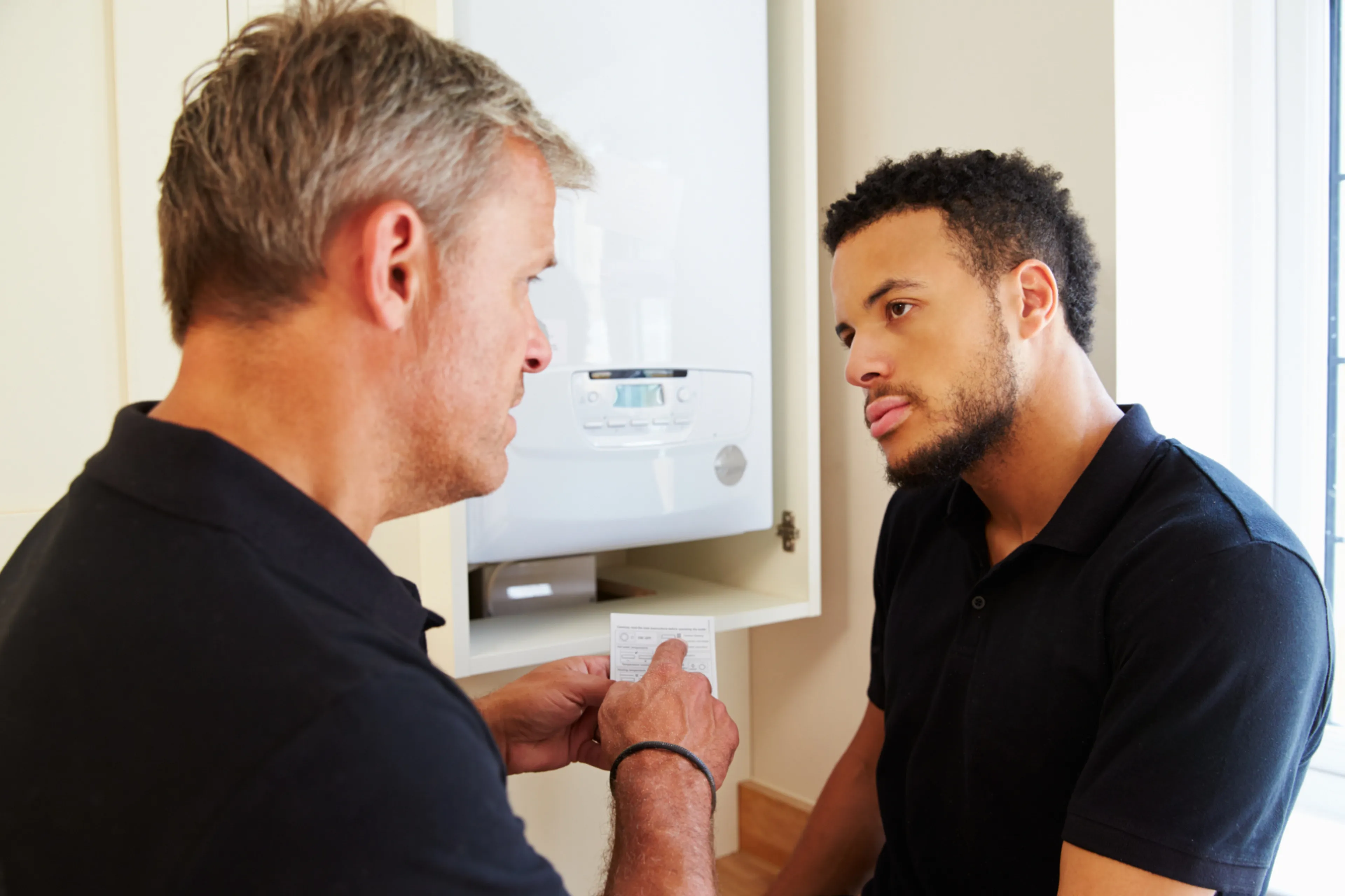 Man geeft instructie aan andere man over cv-ketel. Onderhoud en instelling cv-ketel.