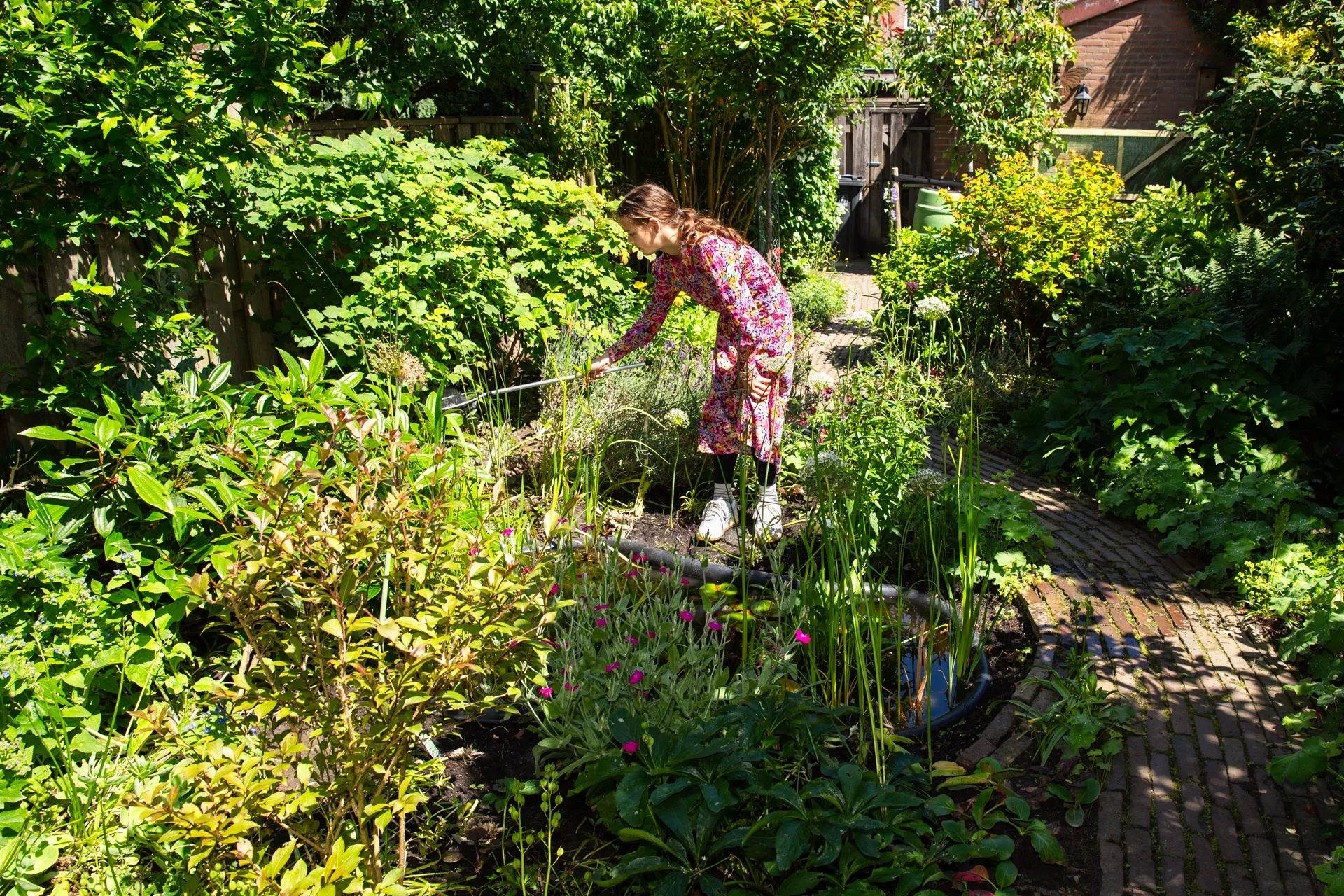meisje met visnetje bij vijver in tuin