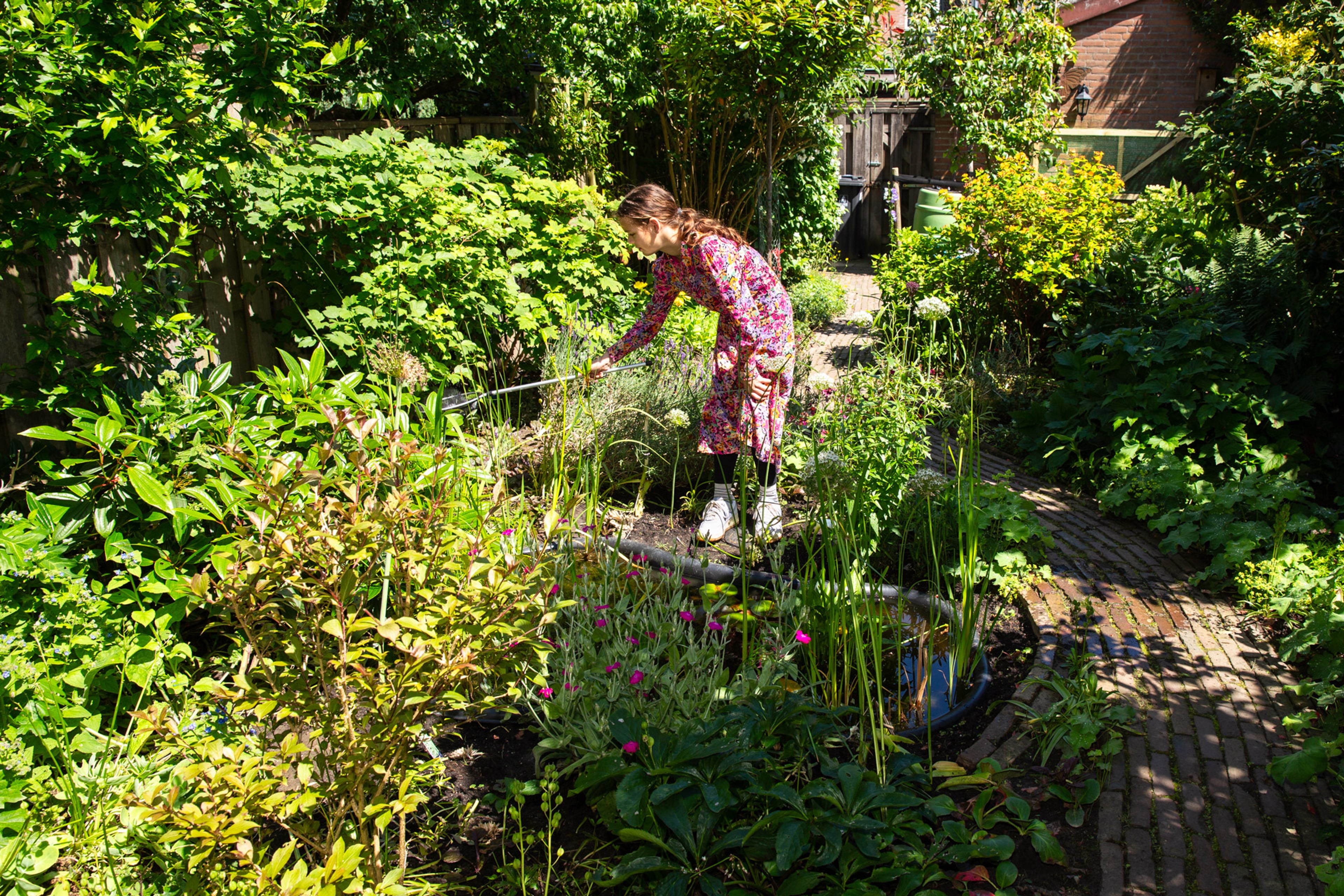 meisje met visnetje bij vijver in tuin