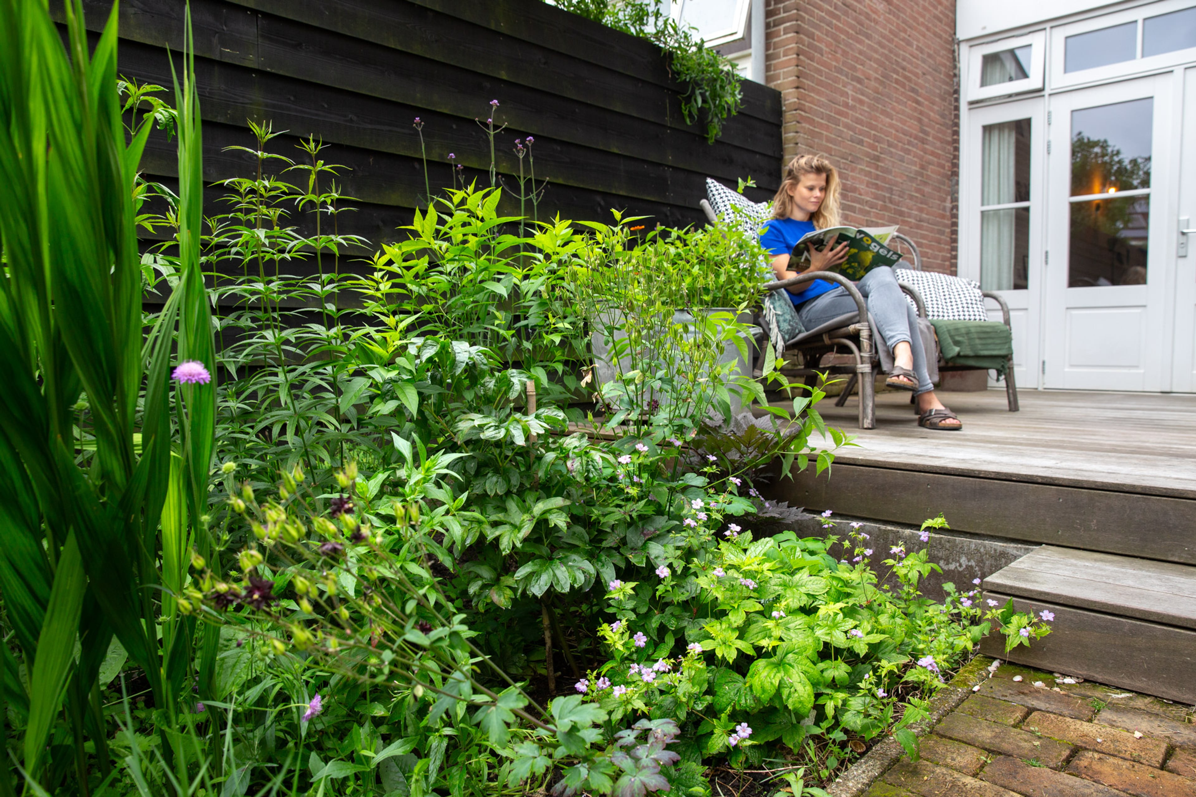 vrouw zit te lezen in stoel in tuin