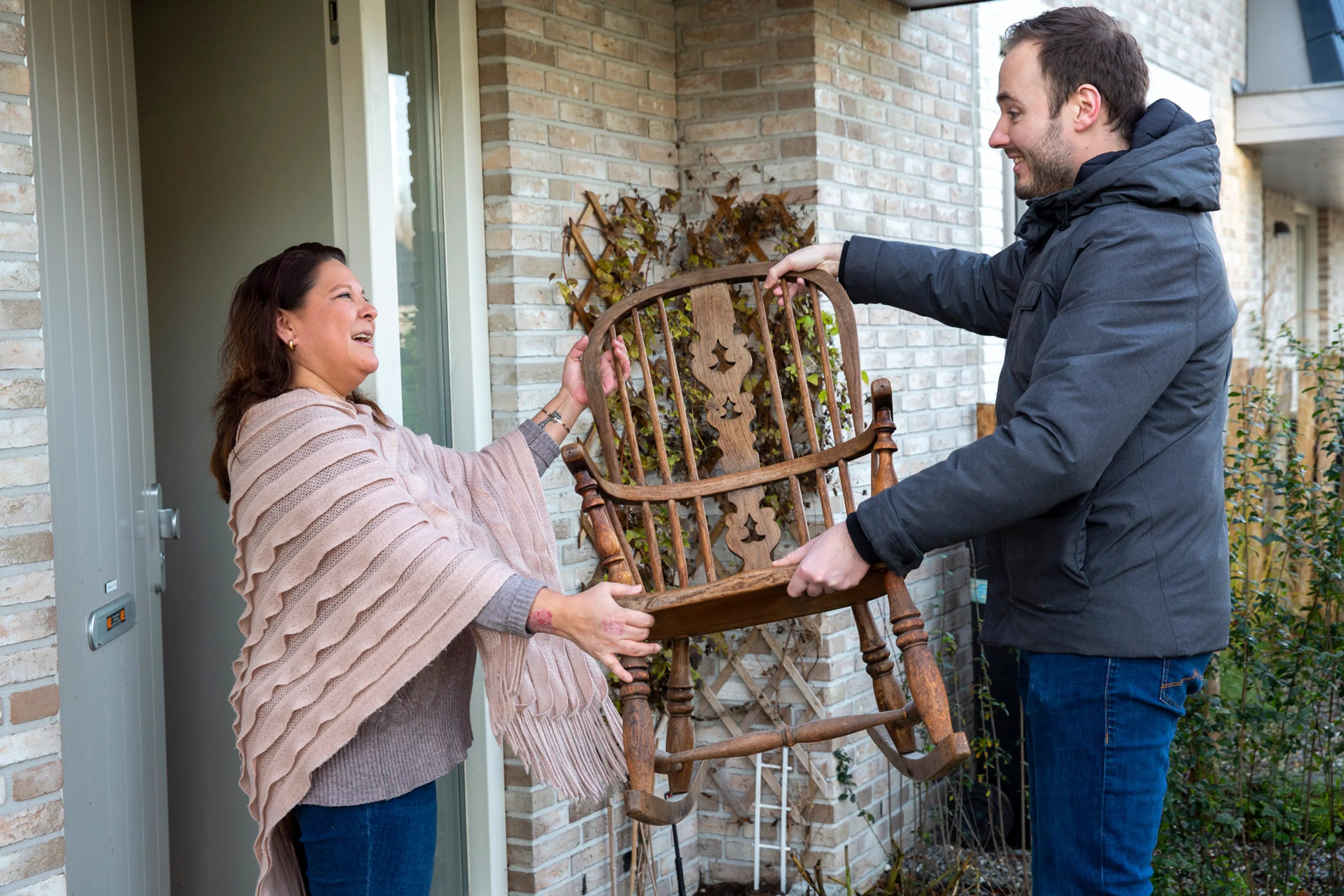 Man geeft een houten schommelstoel aan een vrouw bij de voordeur