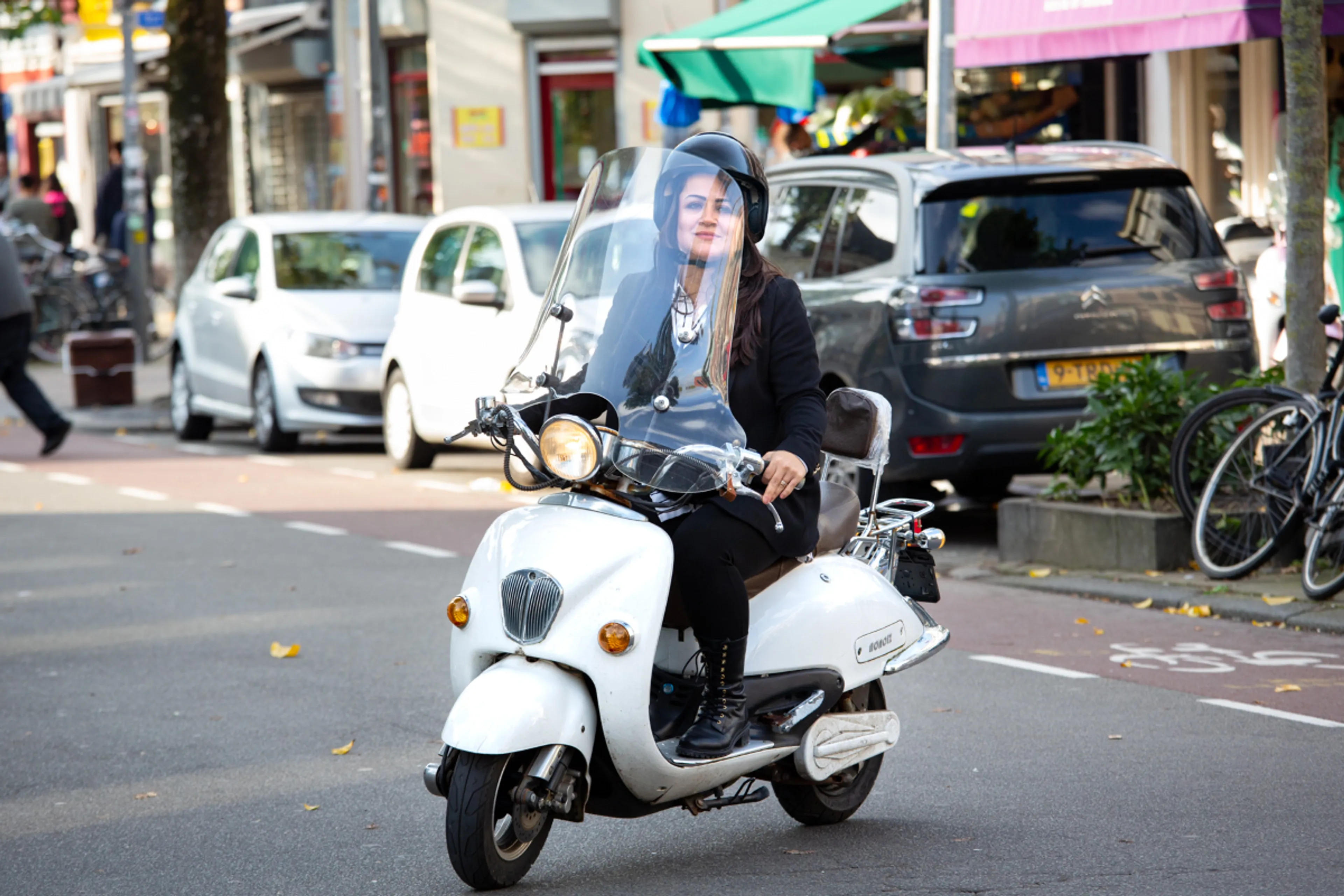 Een vrouw op een elektrische scooter. Elektrische scooters zijn schoner voor het milieu dan benzinescooters.