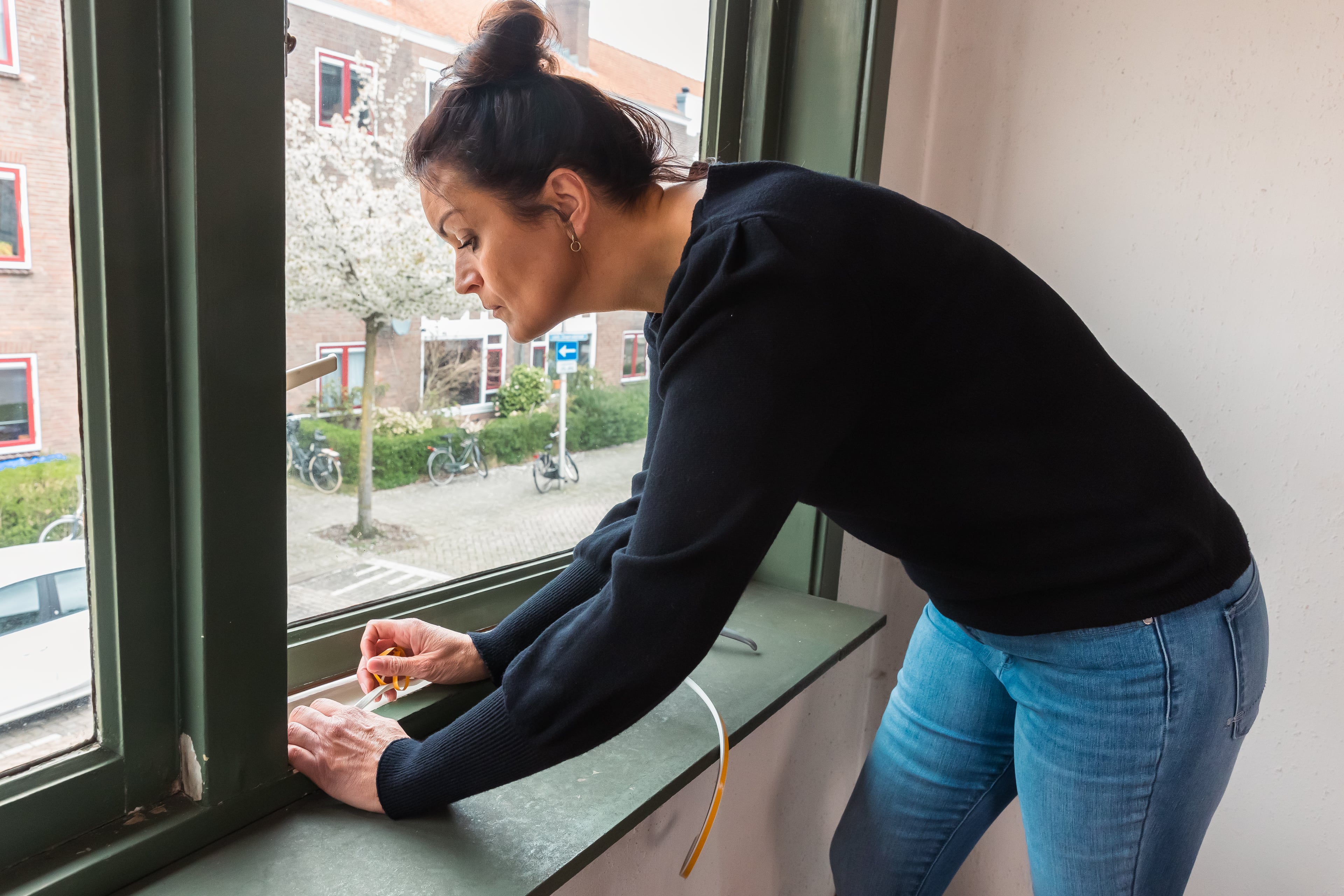 Vrouw plaatst tochtband bij het raam.