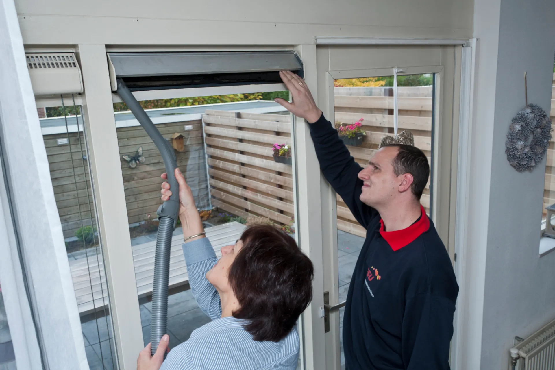 Man en vrouw stofzuigen mechanische ventilatie. Onderhoud en schoonmaak ventilatie.