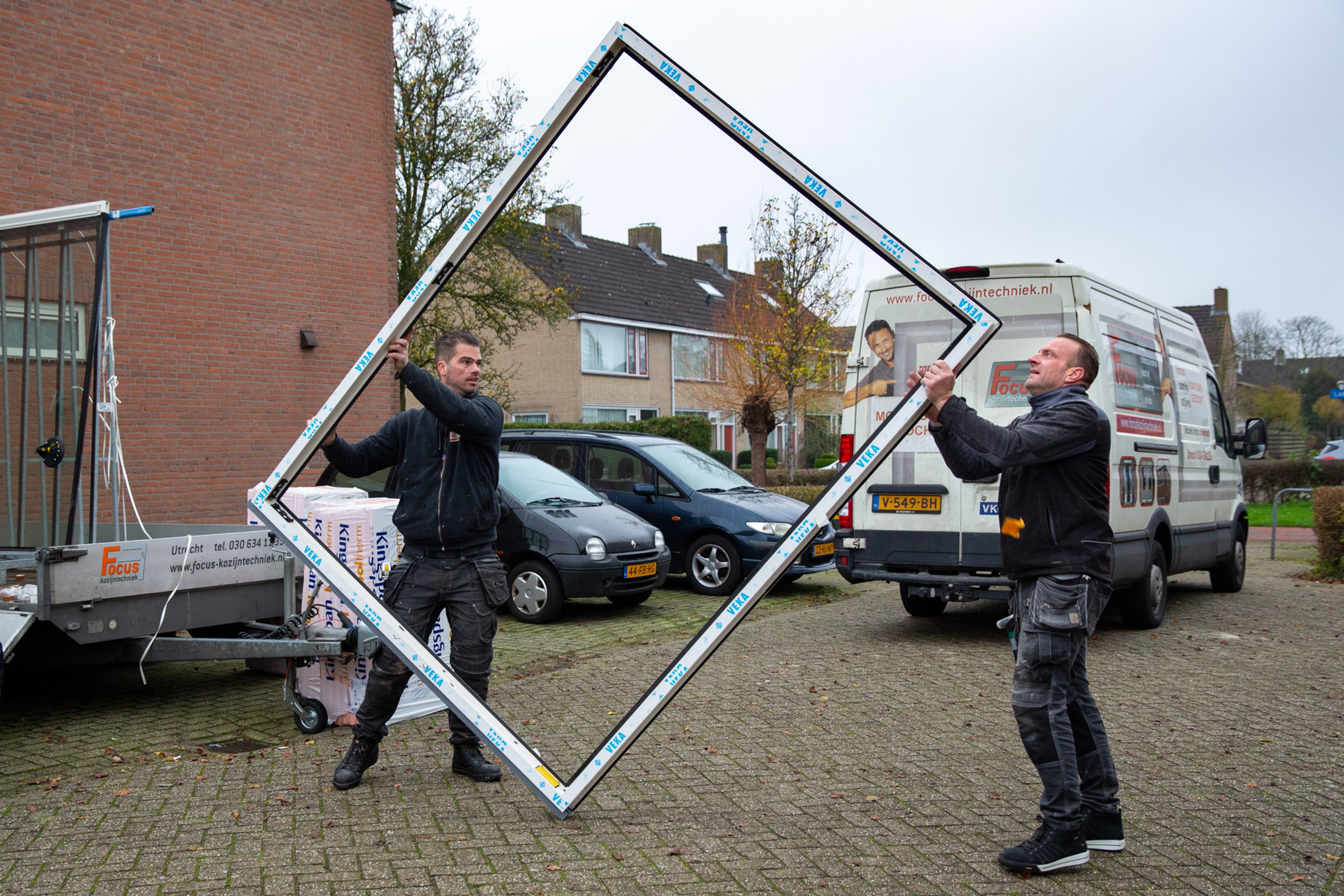 Mannen tillen isolerend kozijn dat ze in huis gaan plaatsen.