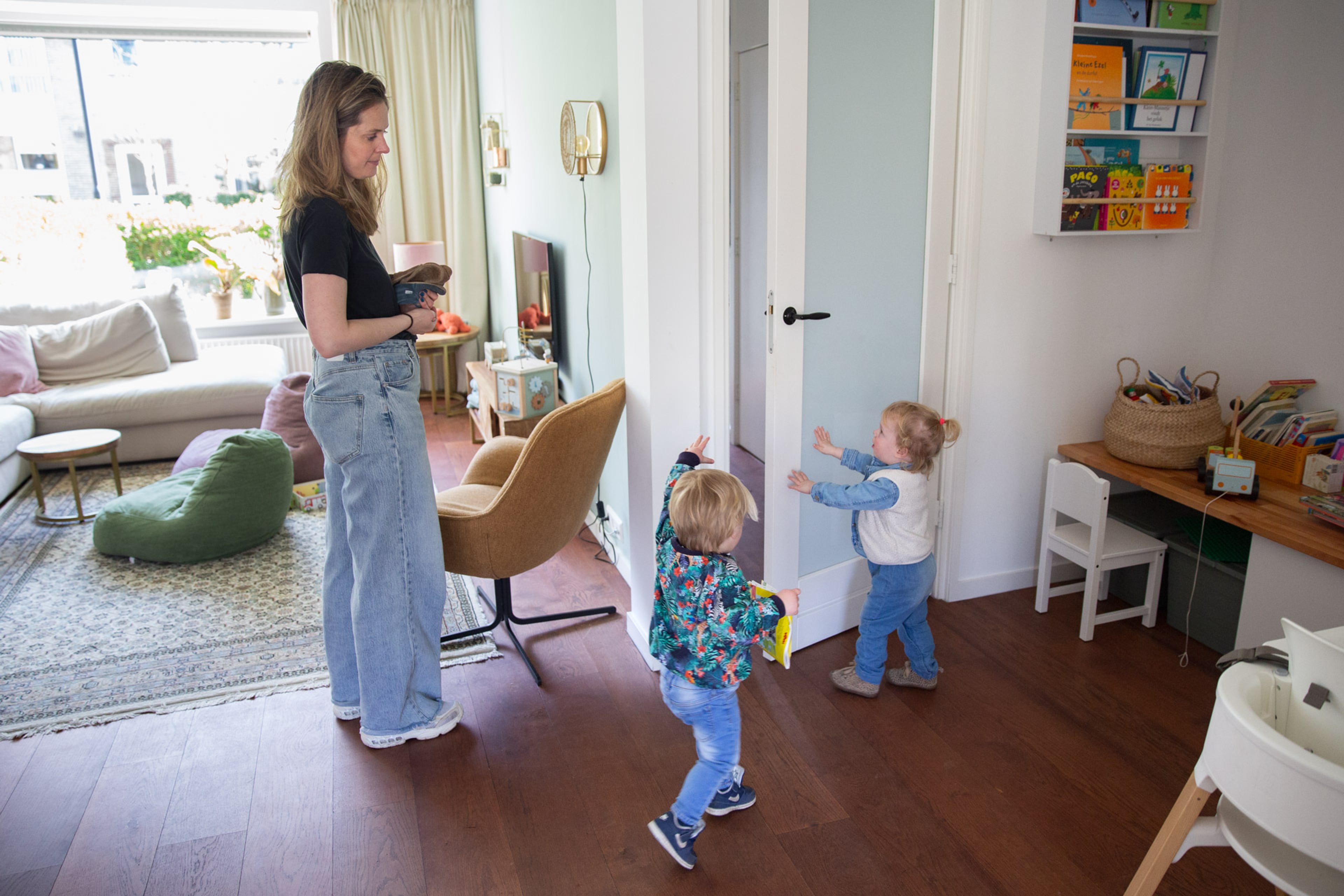 Vrouw en 2 kinderen in de woonkamer sluiten de deur naar de gang. Zo houd je de warmte in de woonkamer.