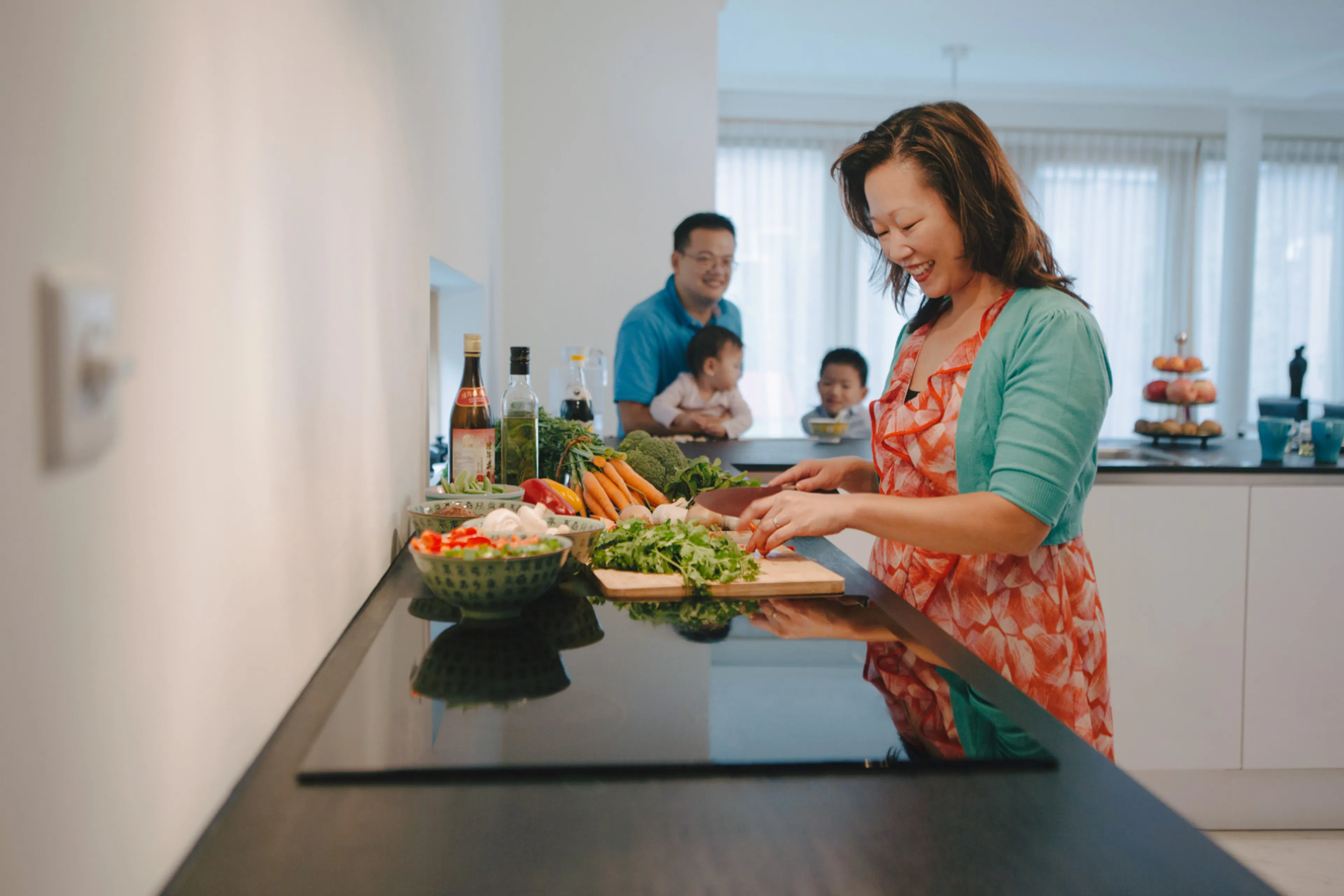 Vrouw snijdt groenten en man en kind staan op de achtergrond. Eten en drinken zorgt voor 20 tot 30 procent van onze milieubelasting.