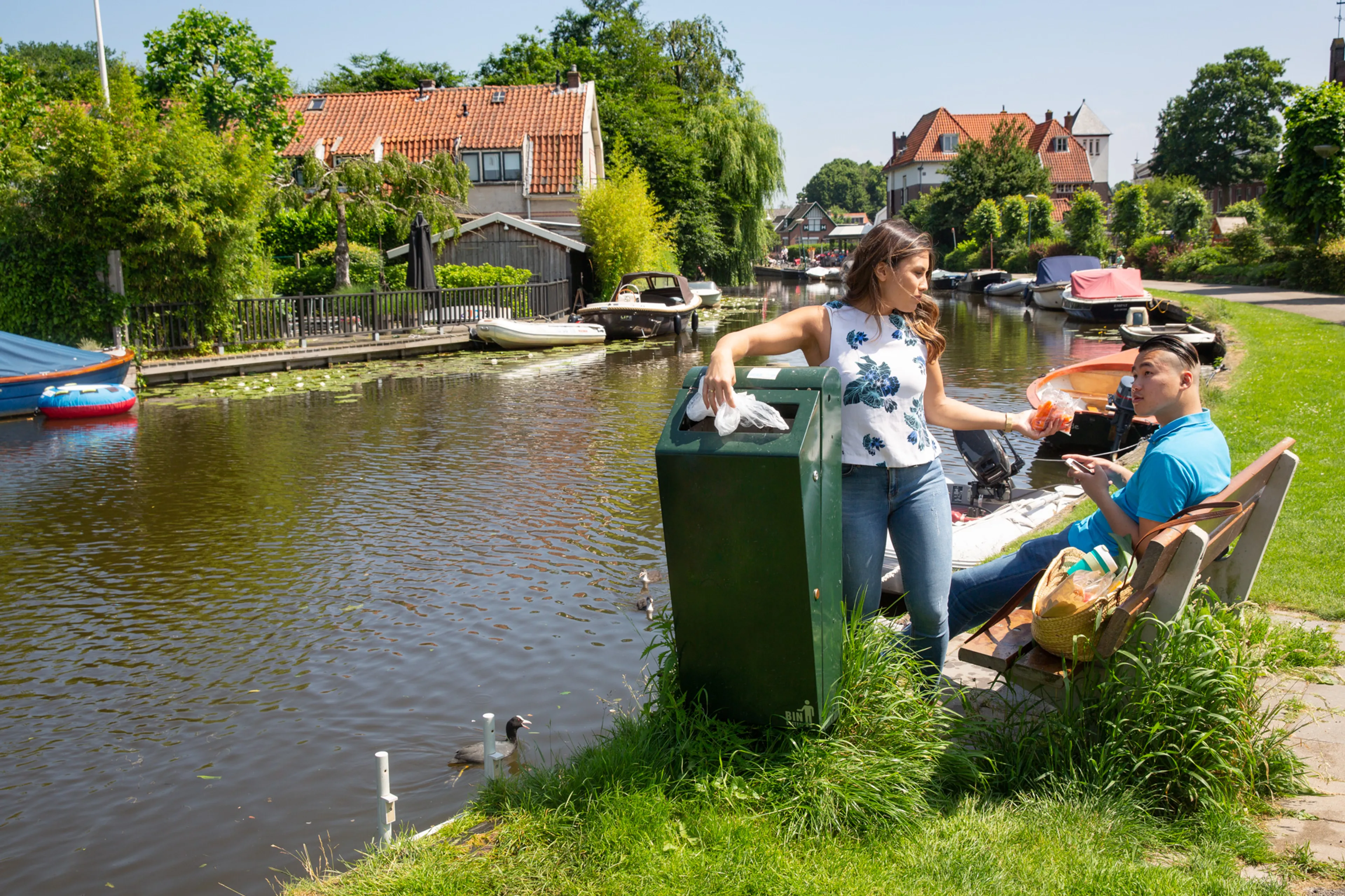 Vrouw gooit plastic in prullenbak. Afval in prullenbak voorkomt zwerfafval.