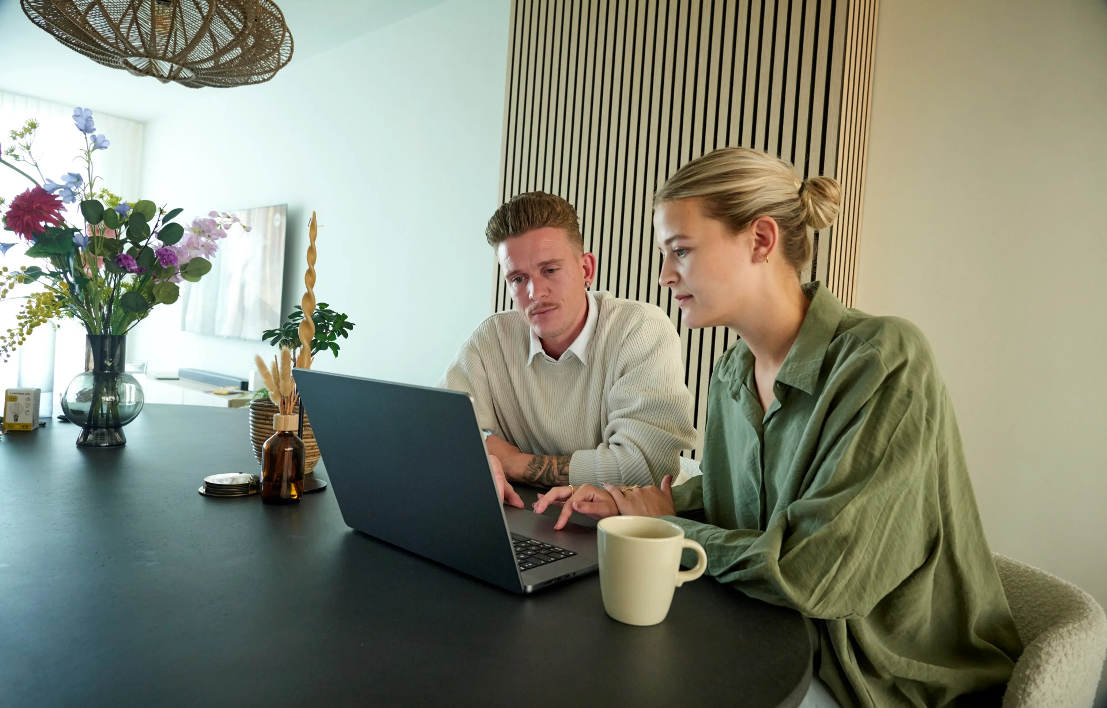 Een stel zit in de zoonkamer en bekijkt een webpagina.