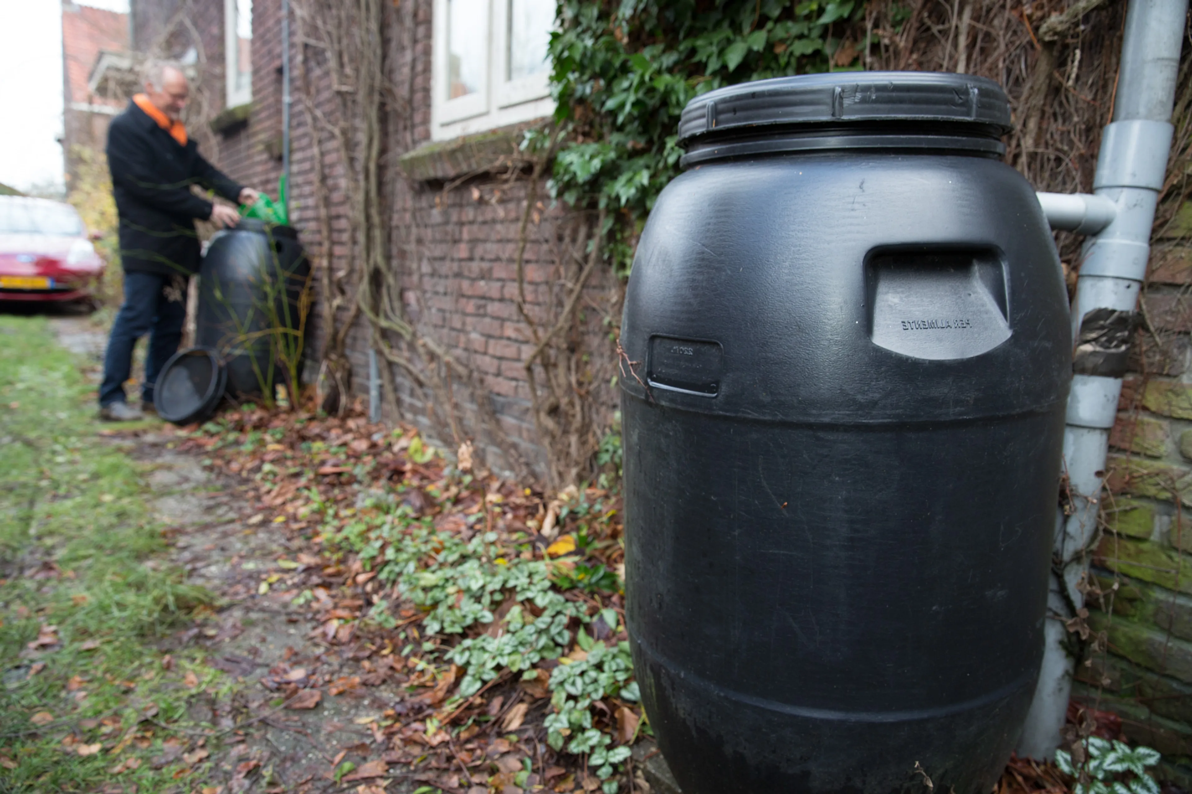 Man is bezig bij watertonnen. Water besparen in tuin.