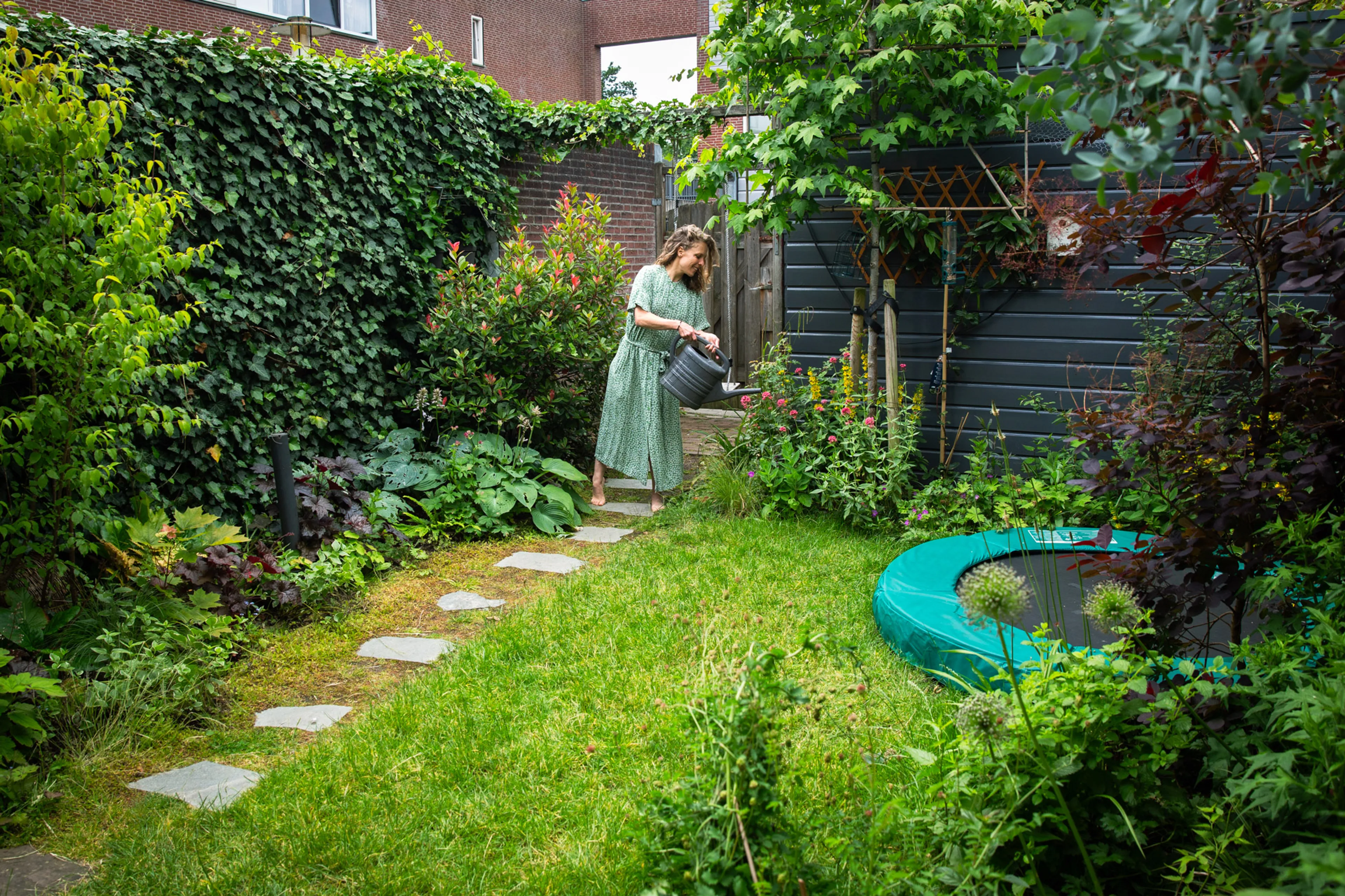 vrouw geeft planten water met gieter in tuin