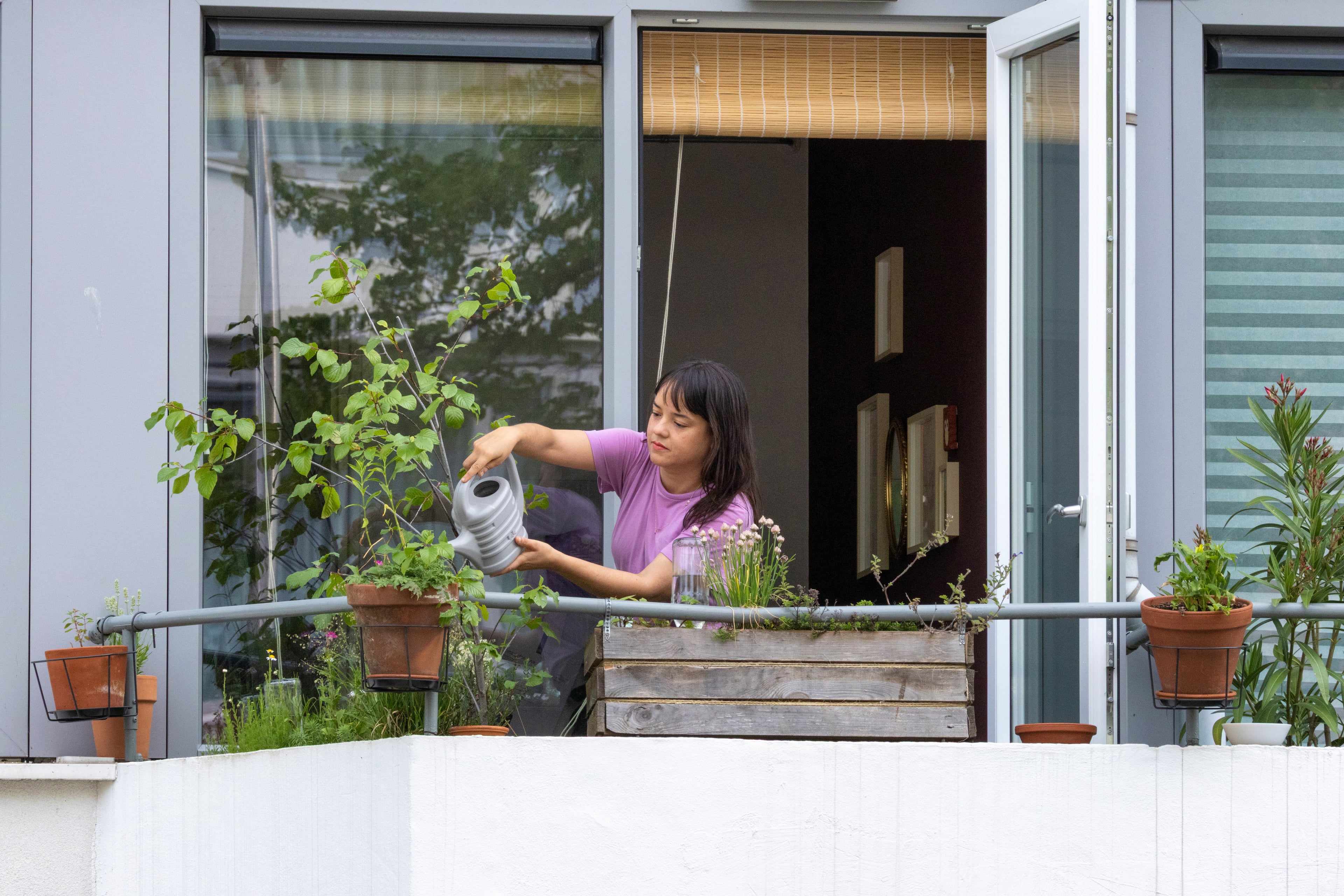 vrouw geeft planten op groen balkon water