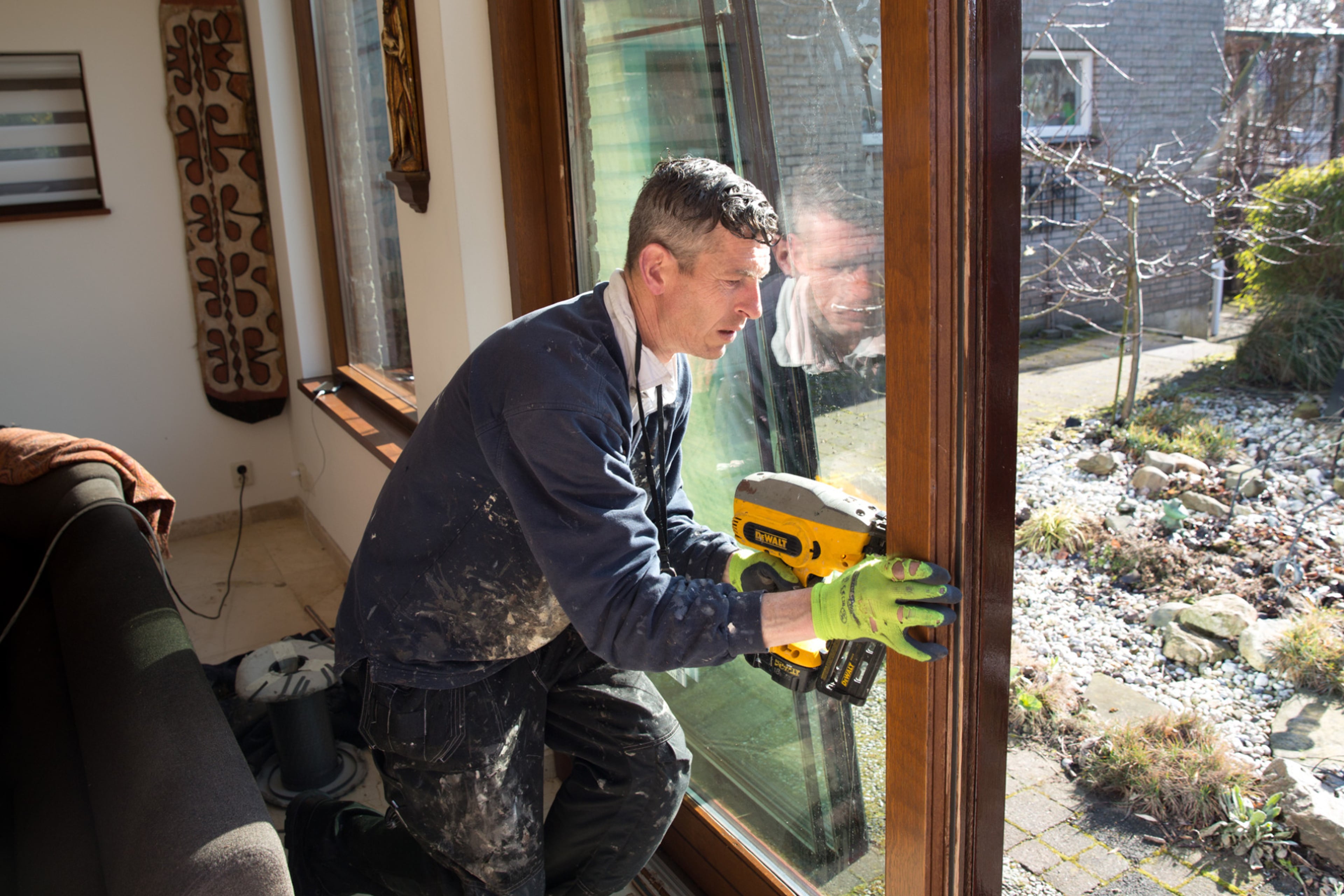 Man schroeft houten latten op het raam waarin net isolerend HR++ glas is geplaatst.