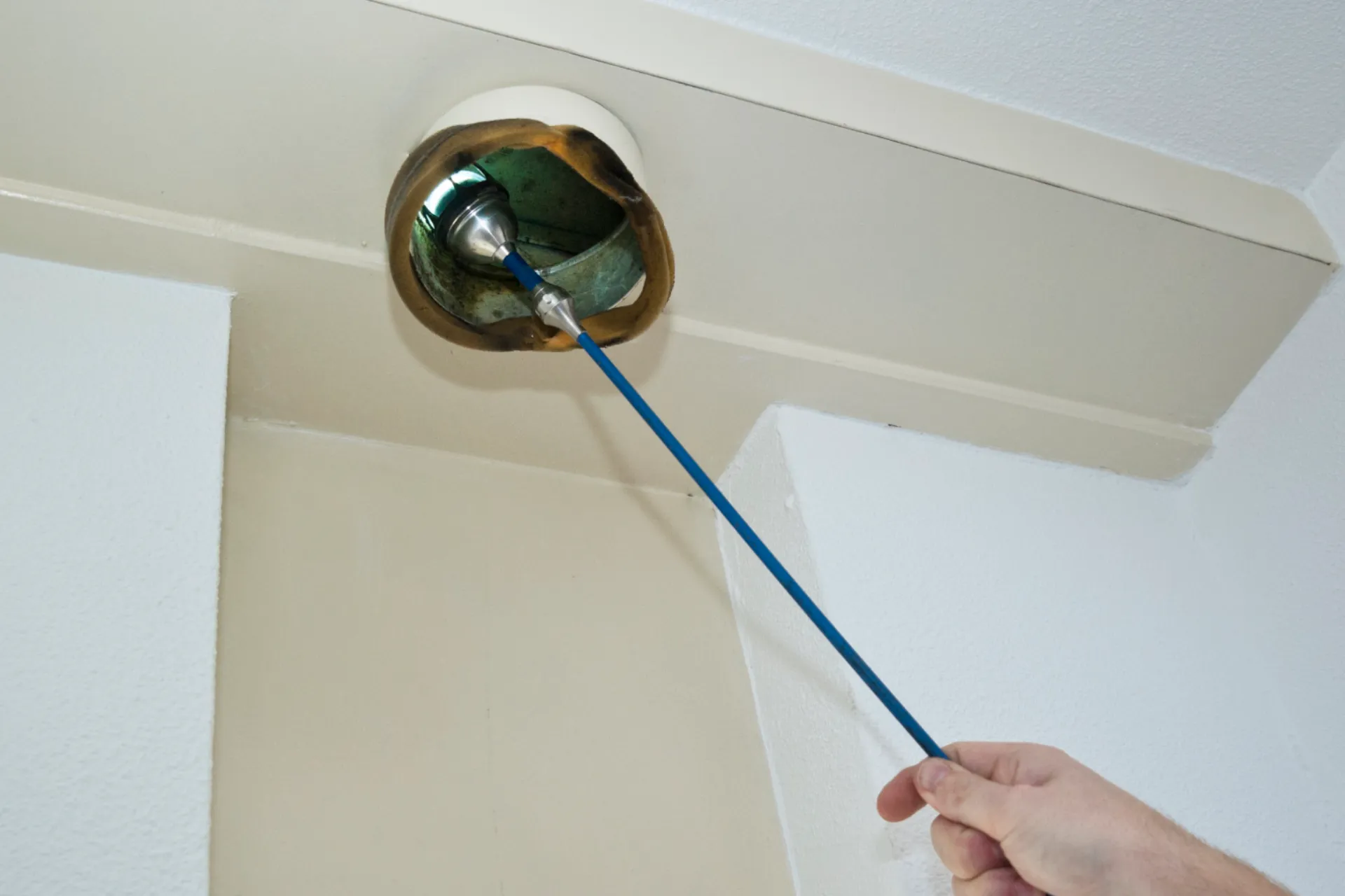 Man inspecteert ventilatie met lampje.