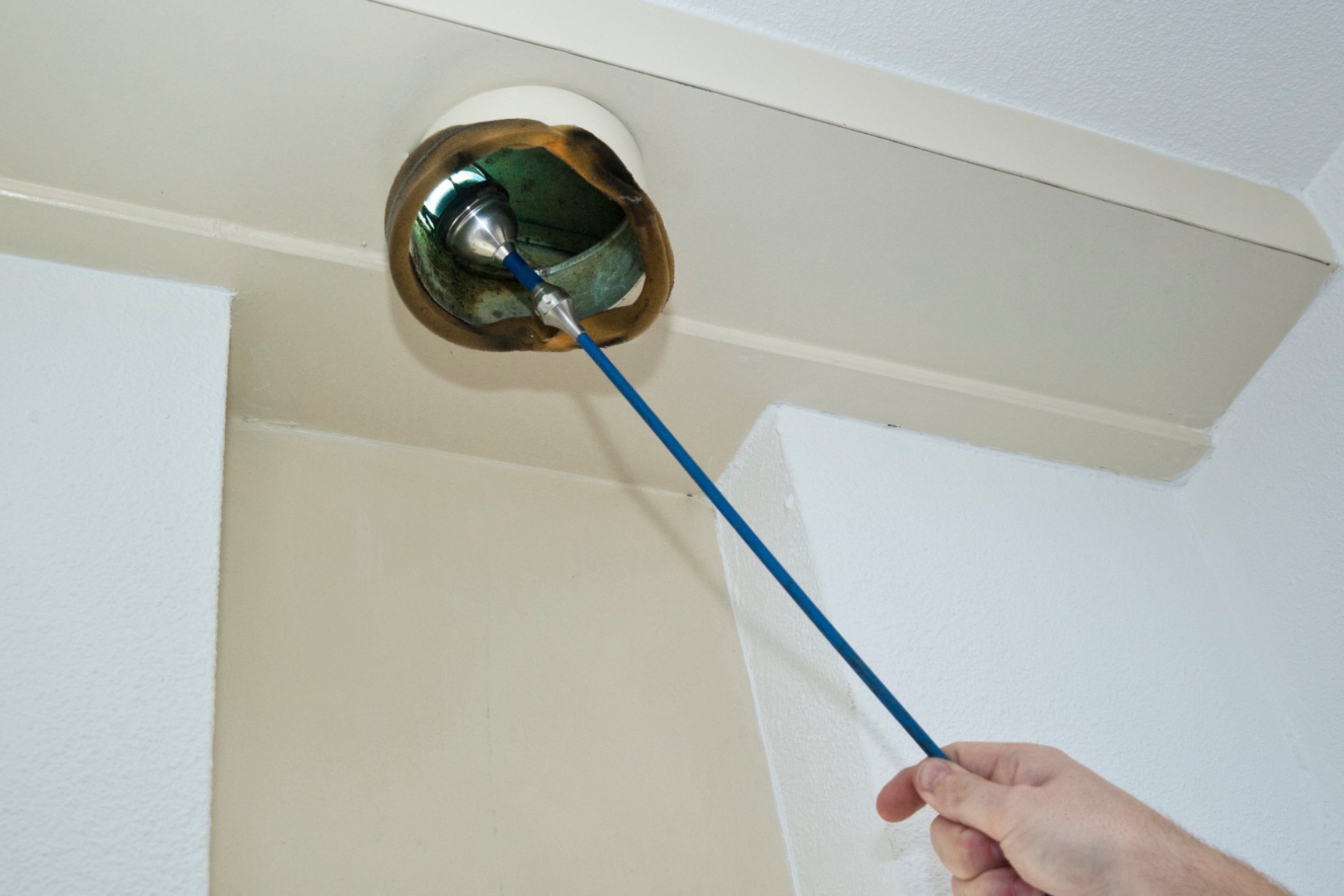 Man inspecteert ventilatie met lampje.