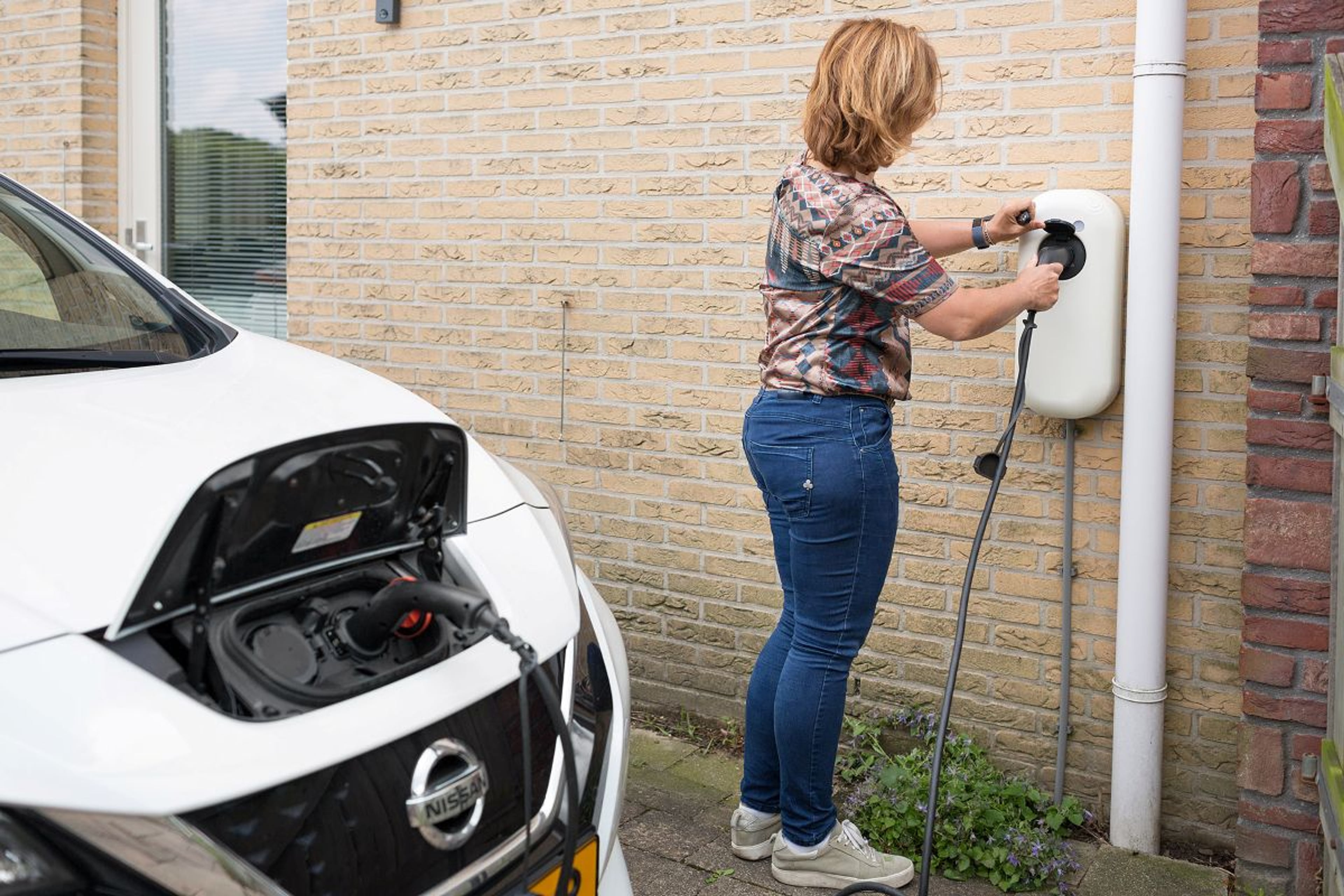 Vrouw laadt elektrische auto op