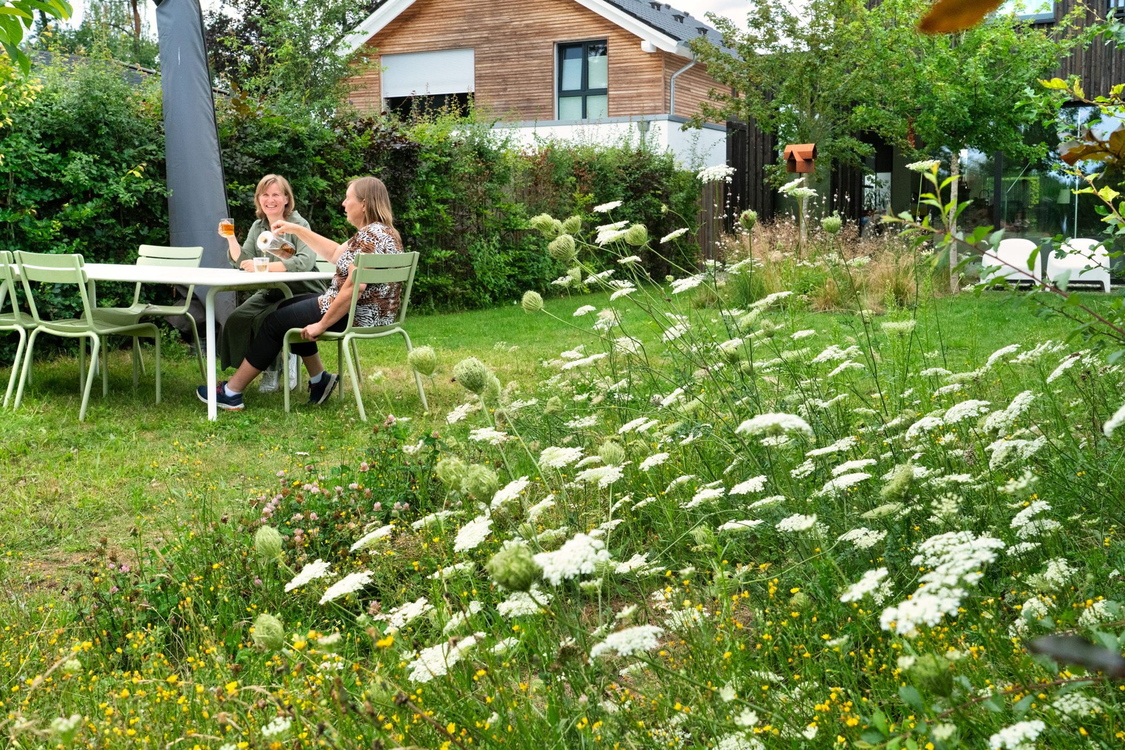Twee vrouwen in tuinzitje in tuin.