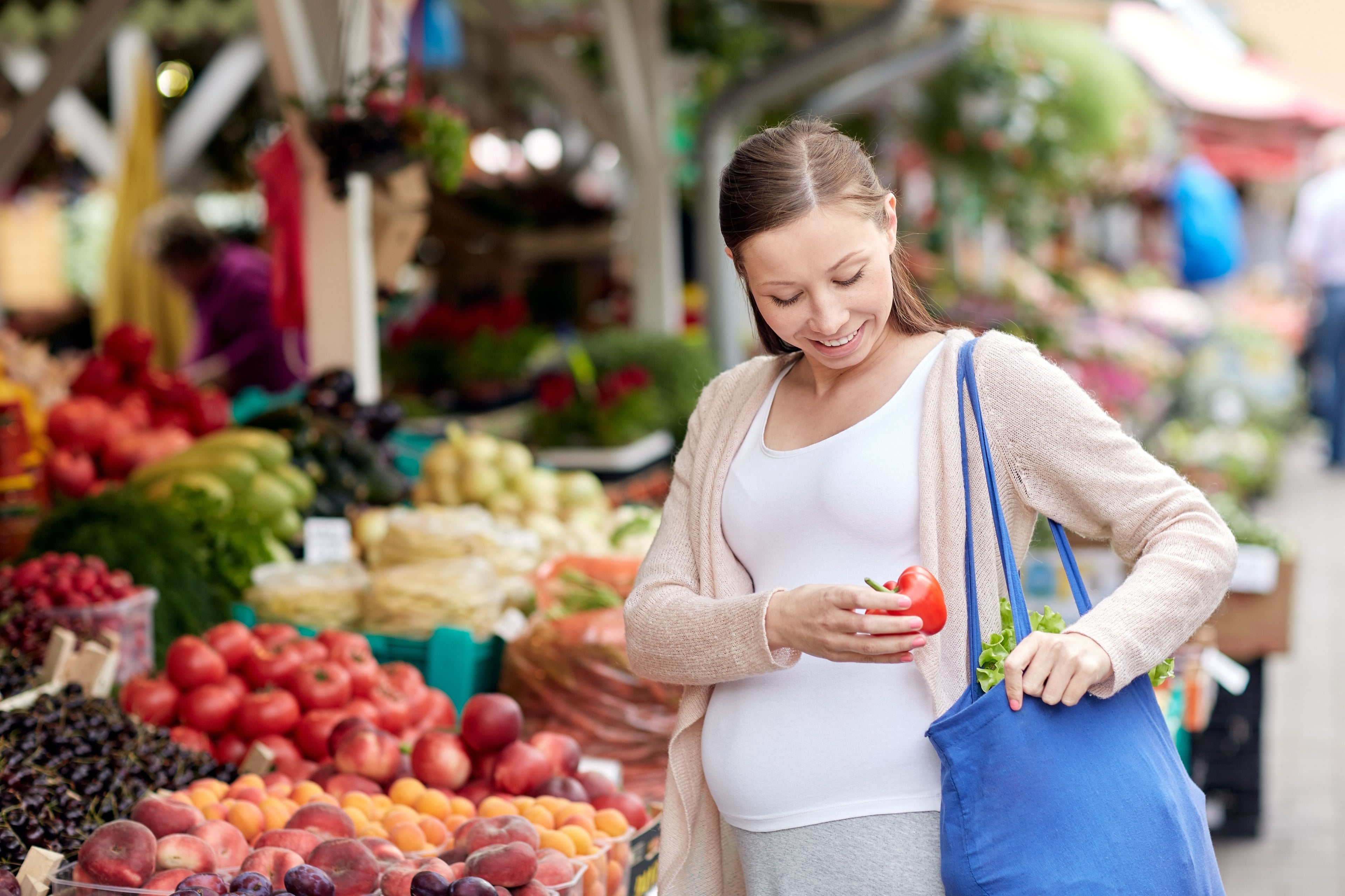 Zwangere vrouw koopt fruit op de markt. Koop eten op maat.