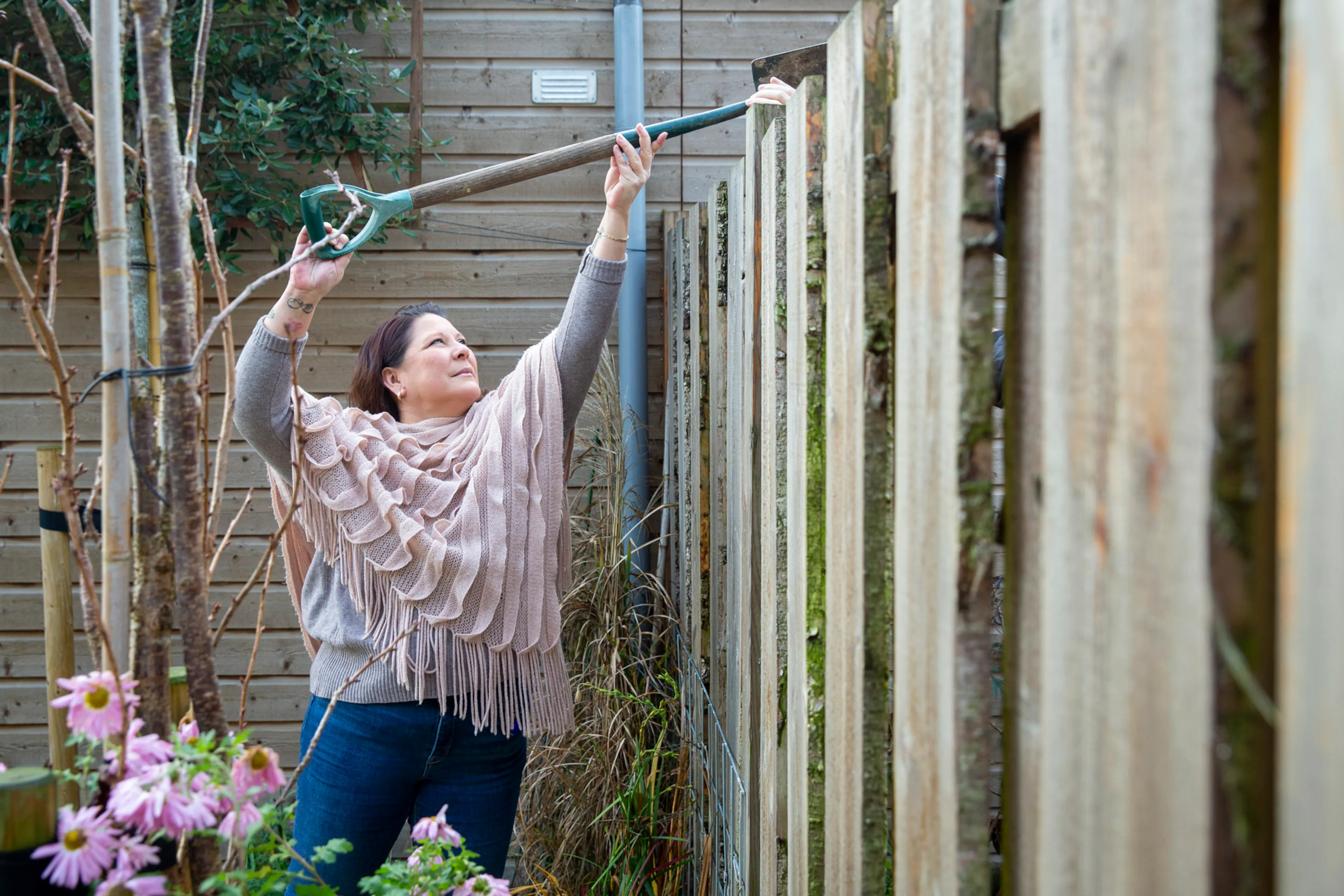 vrouw geeft schep over schutting