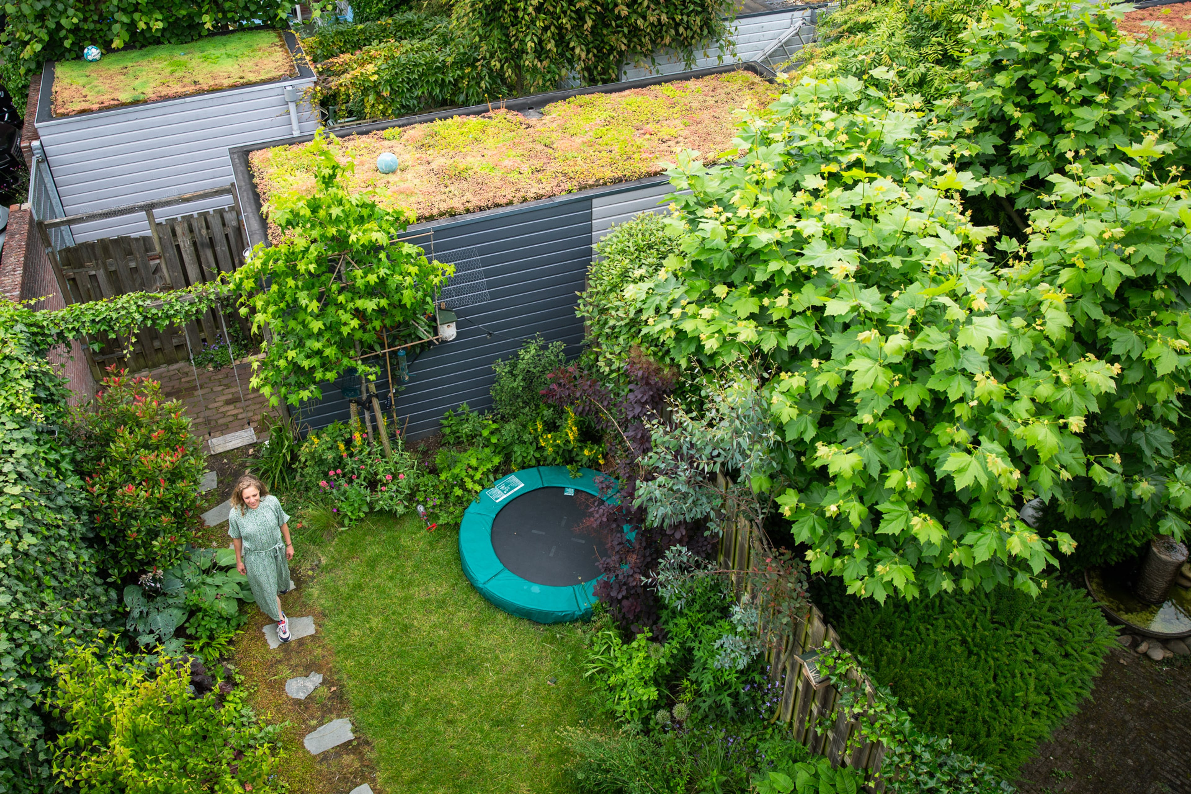 vrouw loopt in tuin met schuur met groen dak