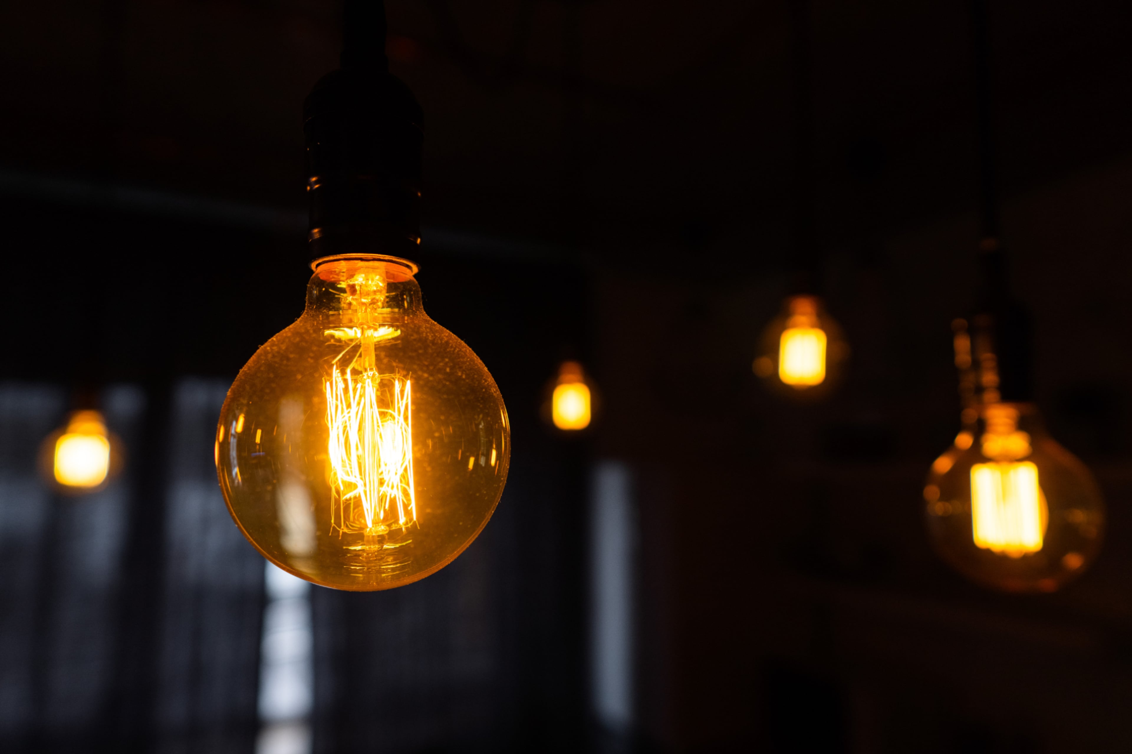 Lampen hangend in het donker. Gloeilampen en halogeenlampen zijn bijna uitgedoofd.