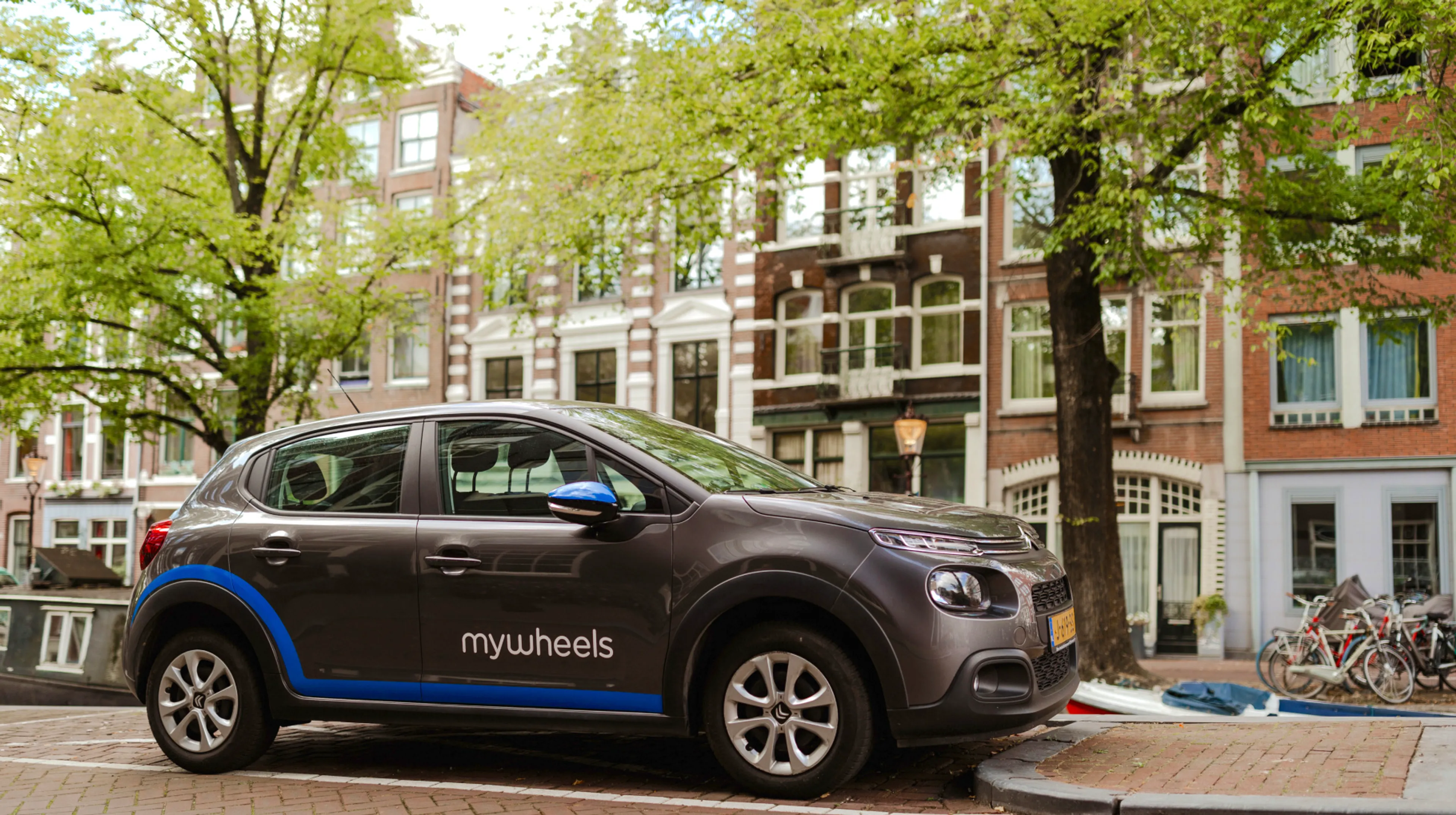 Een deelauto staat geparkeerd aan de Amsterdamse gracht.