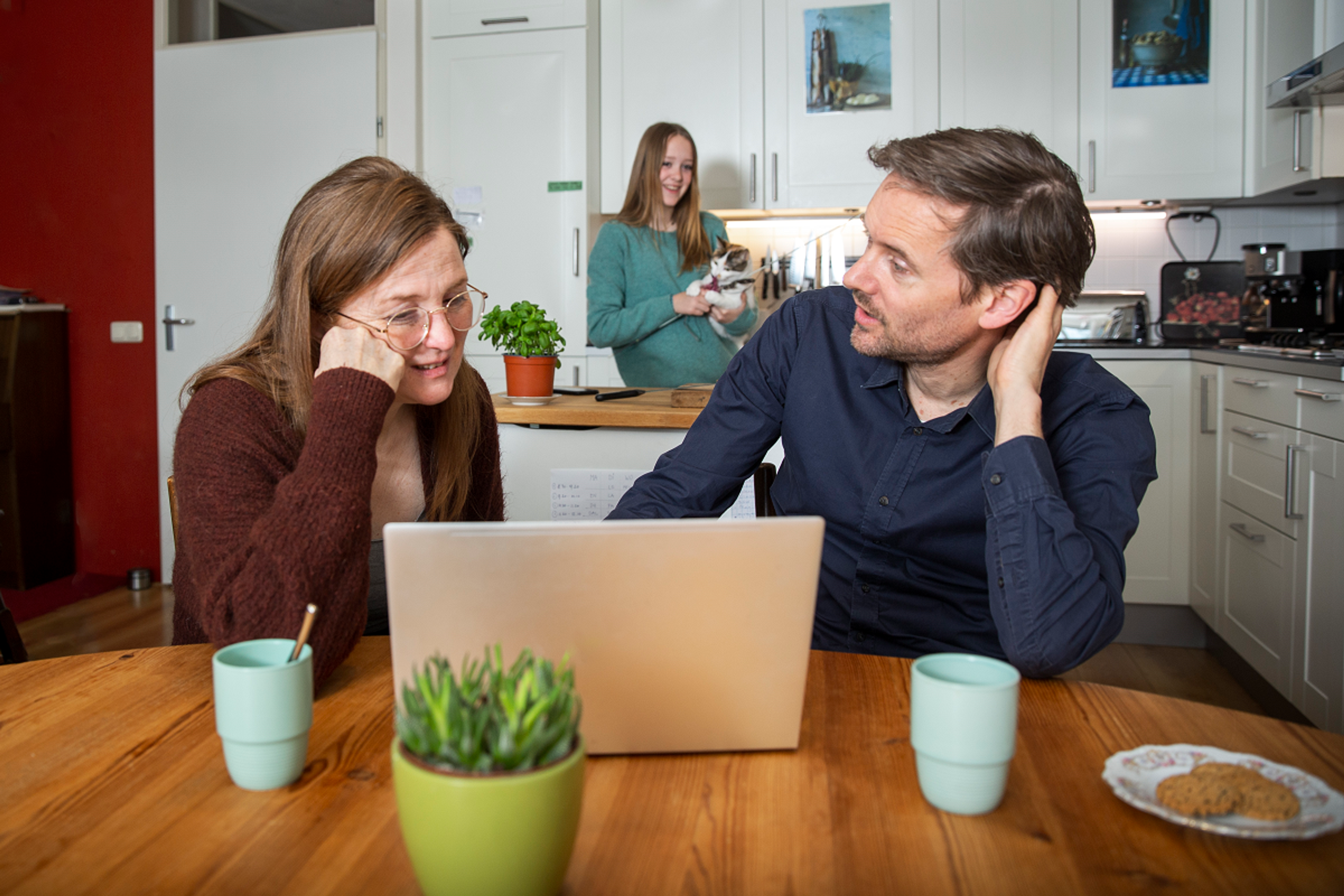 Een stel bespreekt iets wat ze op hun laptop lezen.