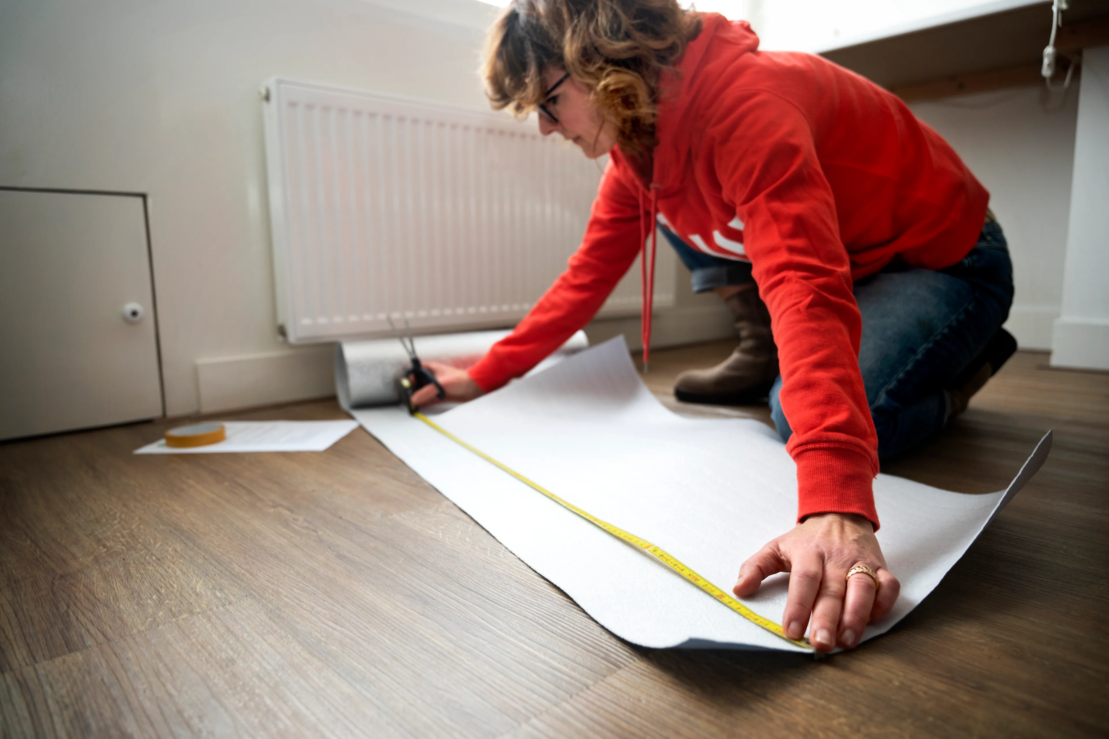 Vrouw meet radiatorfolie op en knipt het op maat