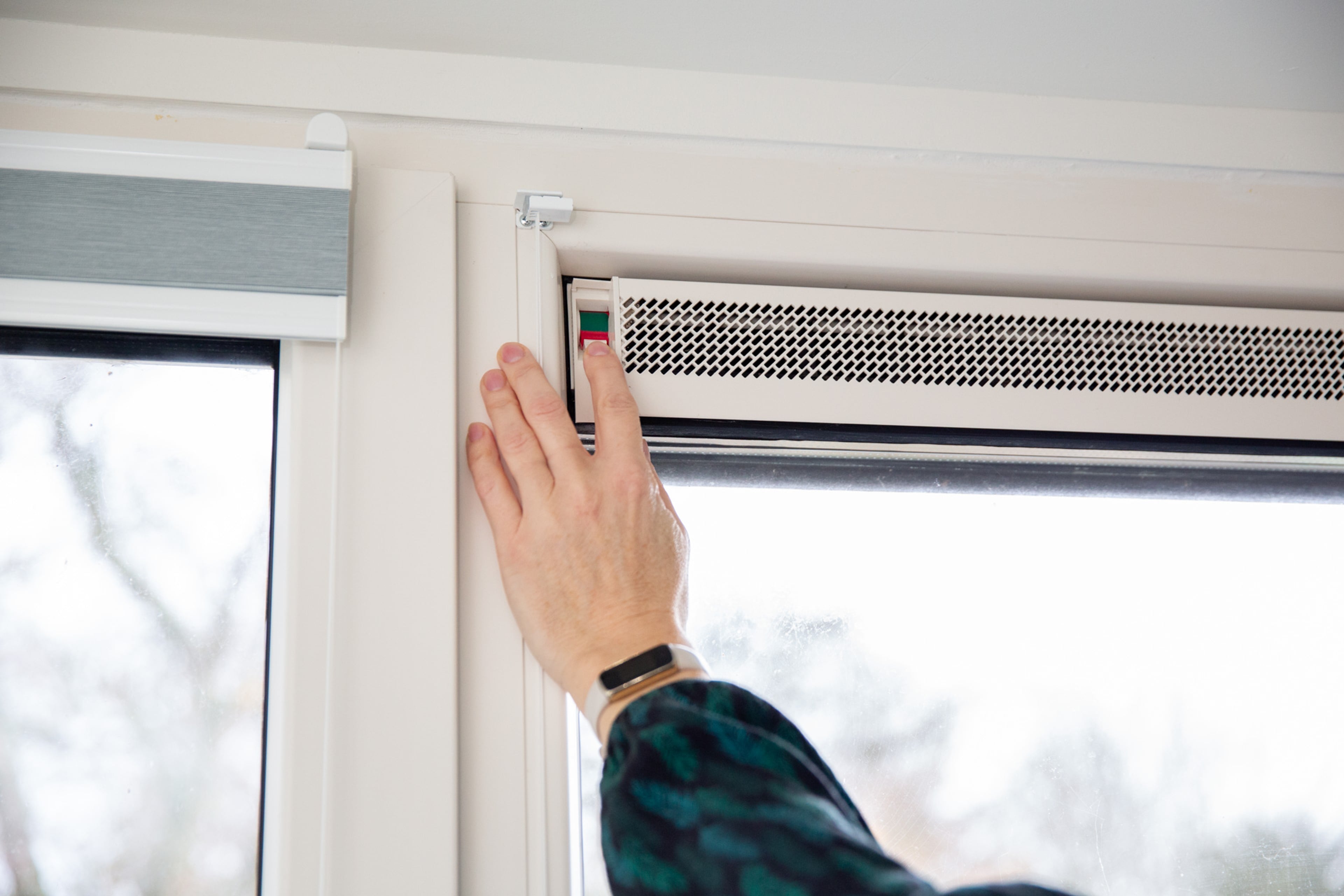 Een vrouw zet het ventilatierooster in de keuken open.