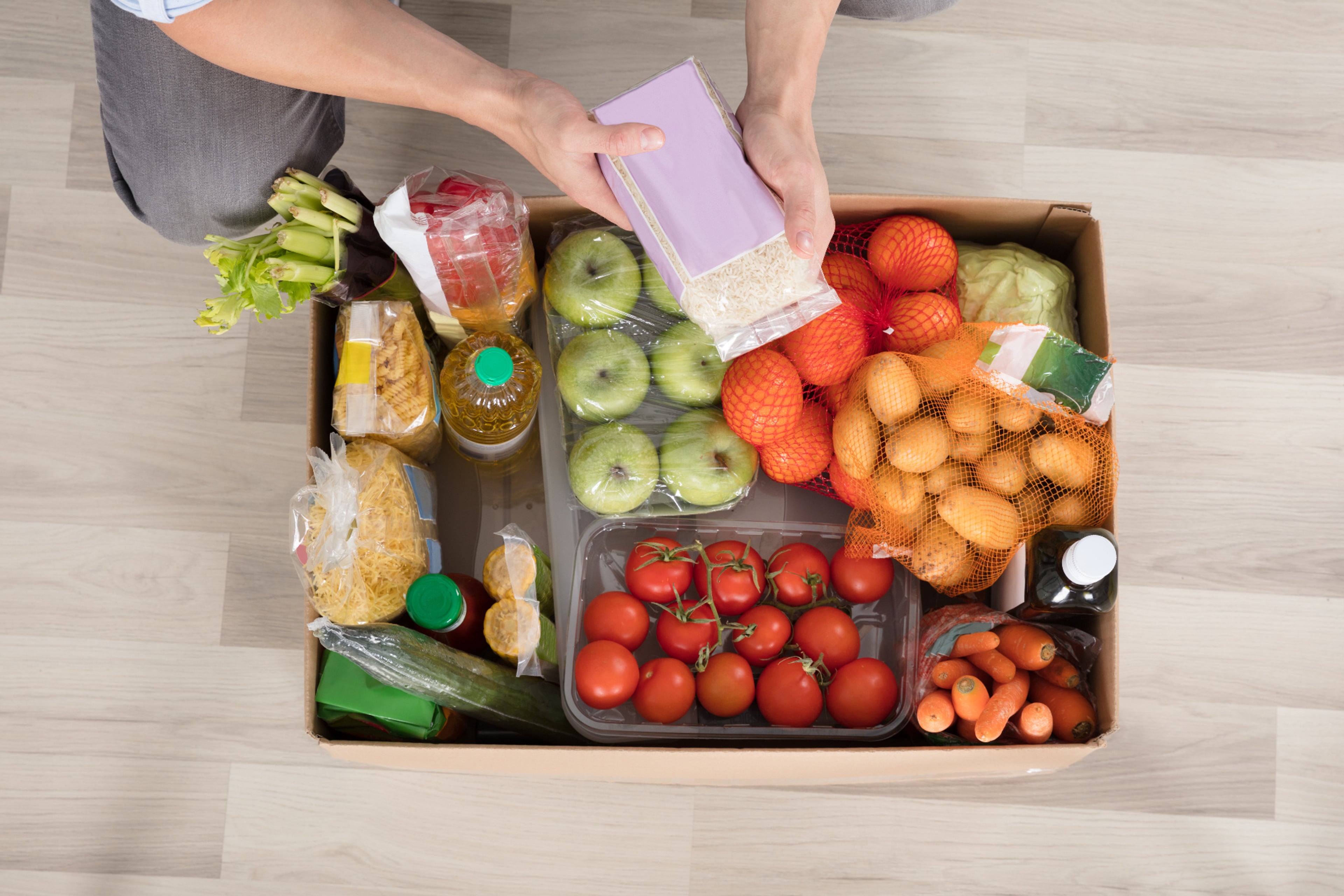 Boodschappen in een kartonnen doos, met heel veel verpakkingen. Verpakkingen verminderen is eenvoudig te doen met je eigen groente- en fruitnetjes. aantal verpakkingen verminderen.