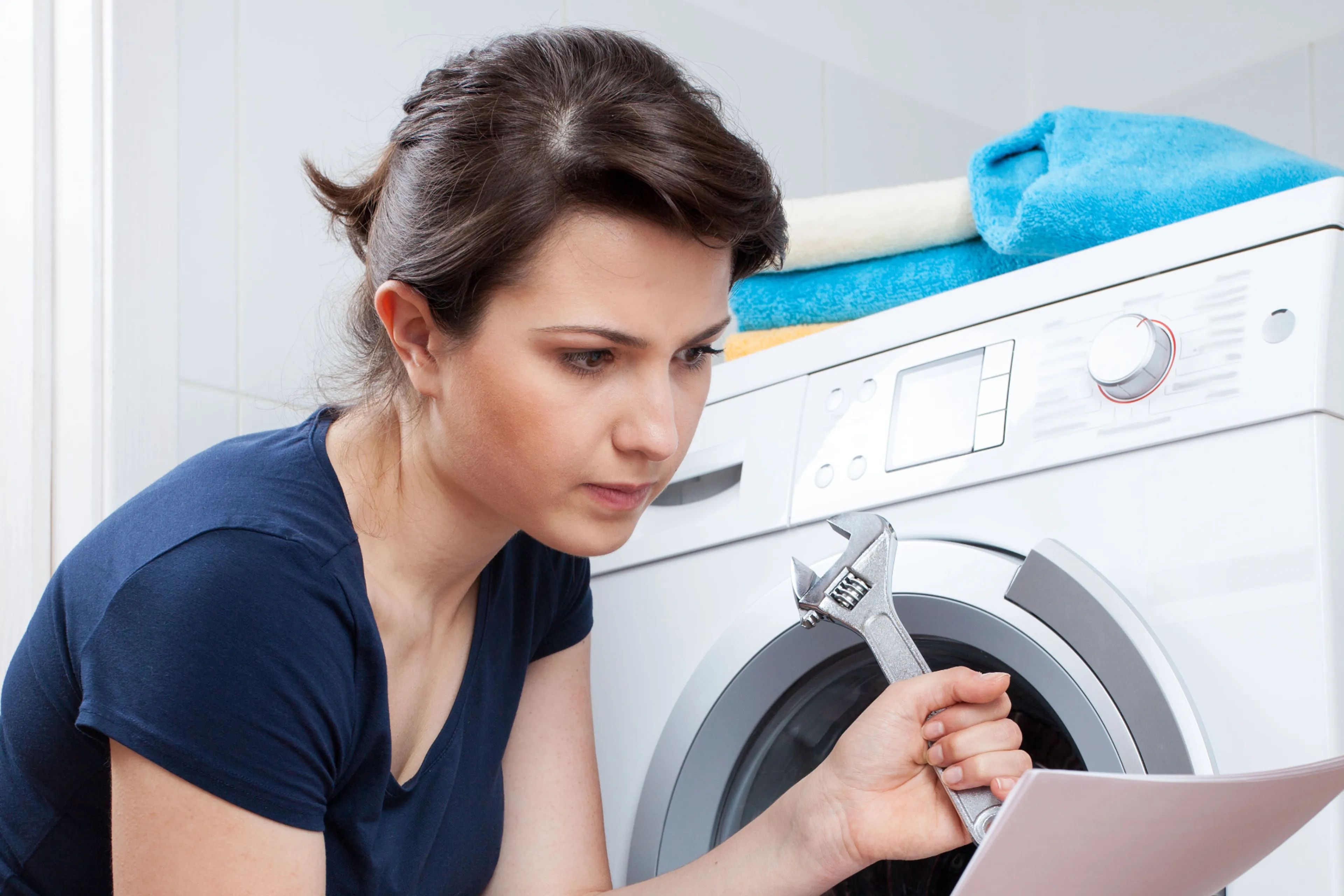 Vrouw repareert wasmachine. Repareren is bijna altijd het beste voor het milieu.