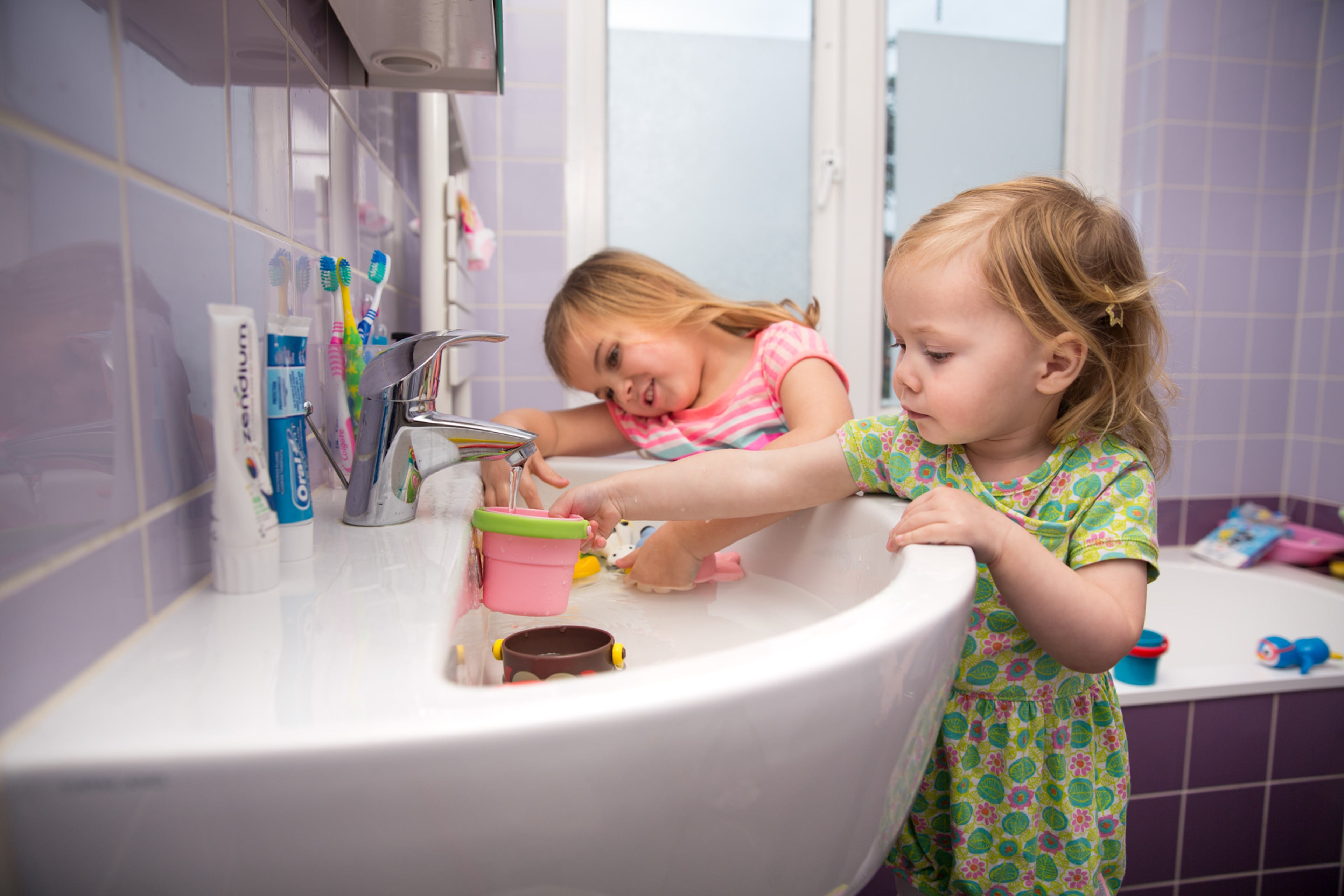 Kinderen spelen met speelgoed in de badkamer. Bespaartips warm water.