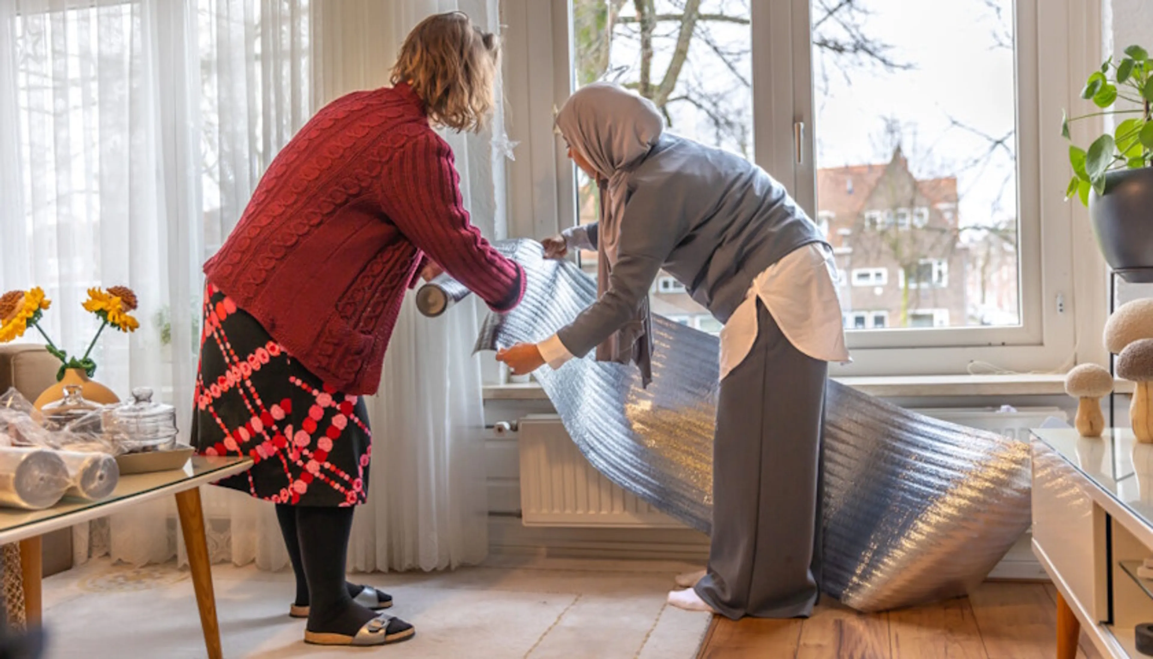 Twee vrouwen installeren samen een rol radiatorfolie