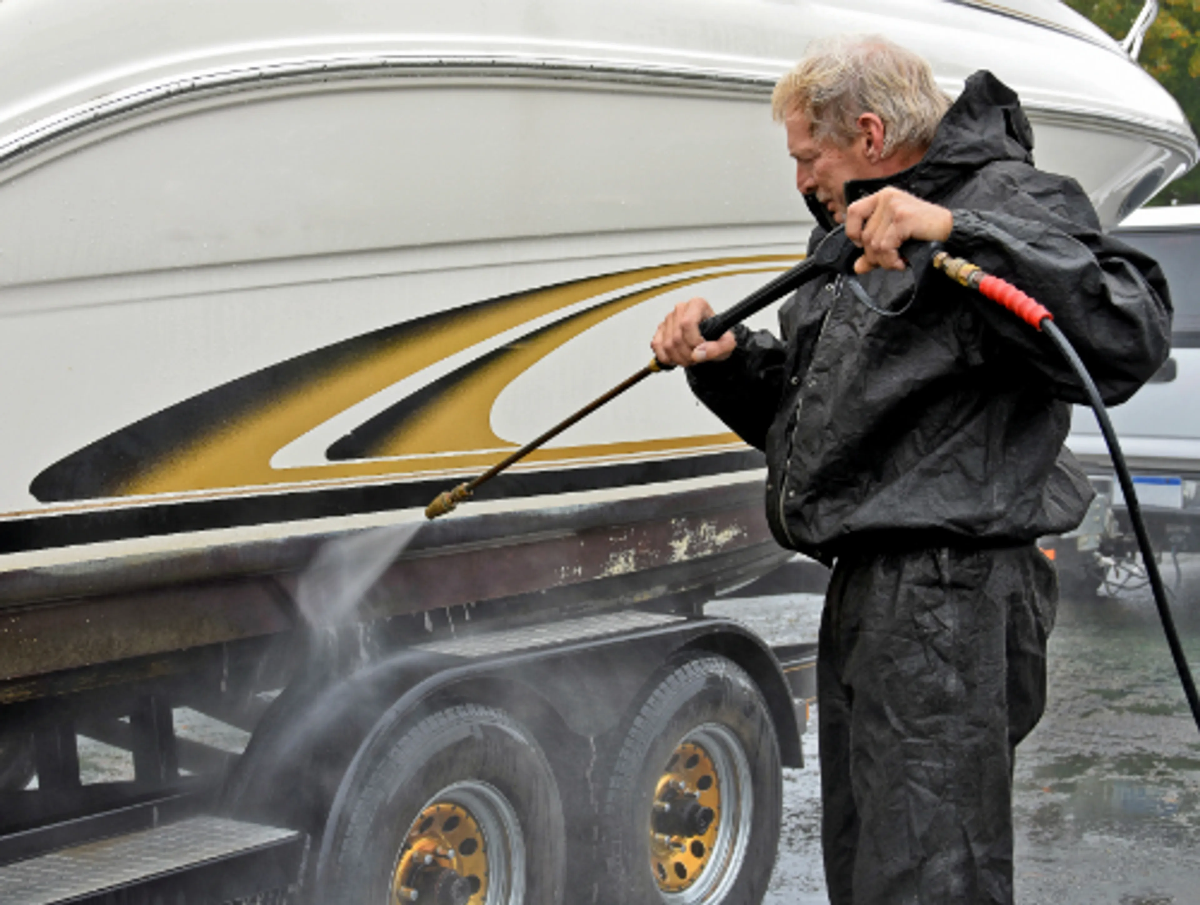 Man reinigt boot met waterspuit. Antifouling.