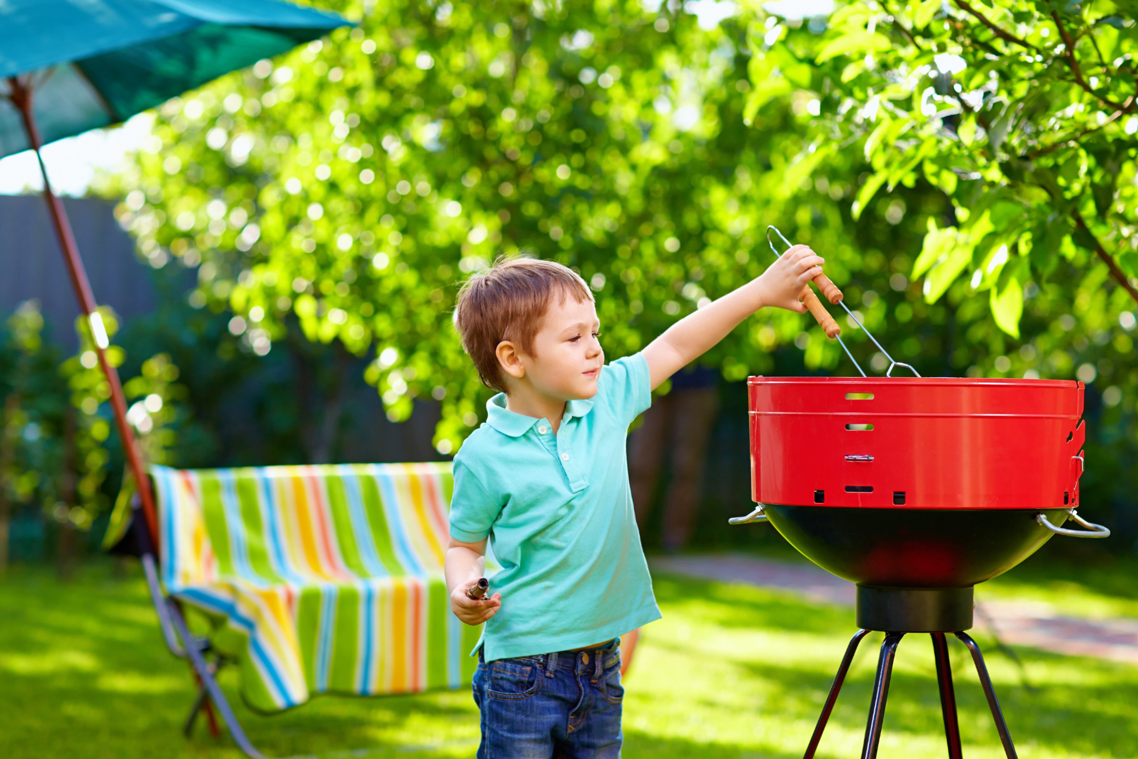 Kind staat bij barbecue. Tips voor een milieuvriendelijke barbecue.